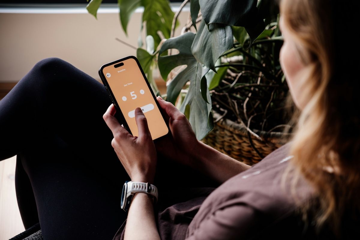 A woman sitting in a chair, using a meditation app to help reach her mental health goals.