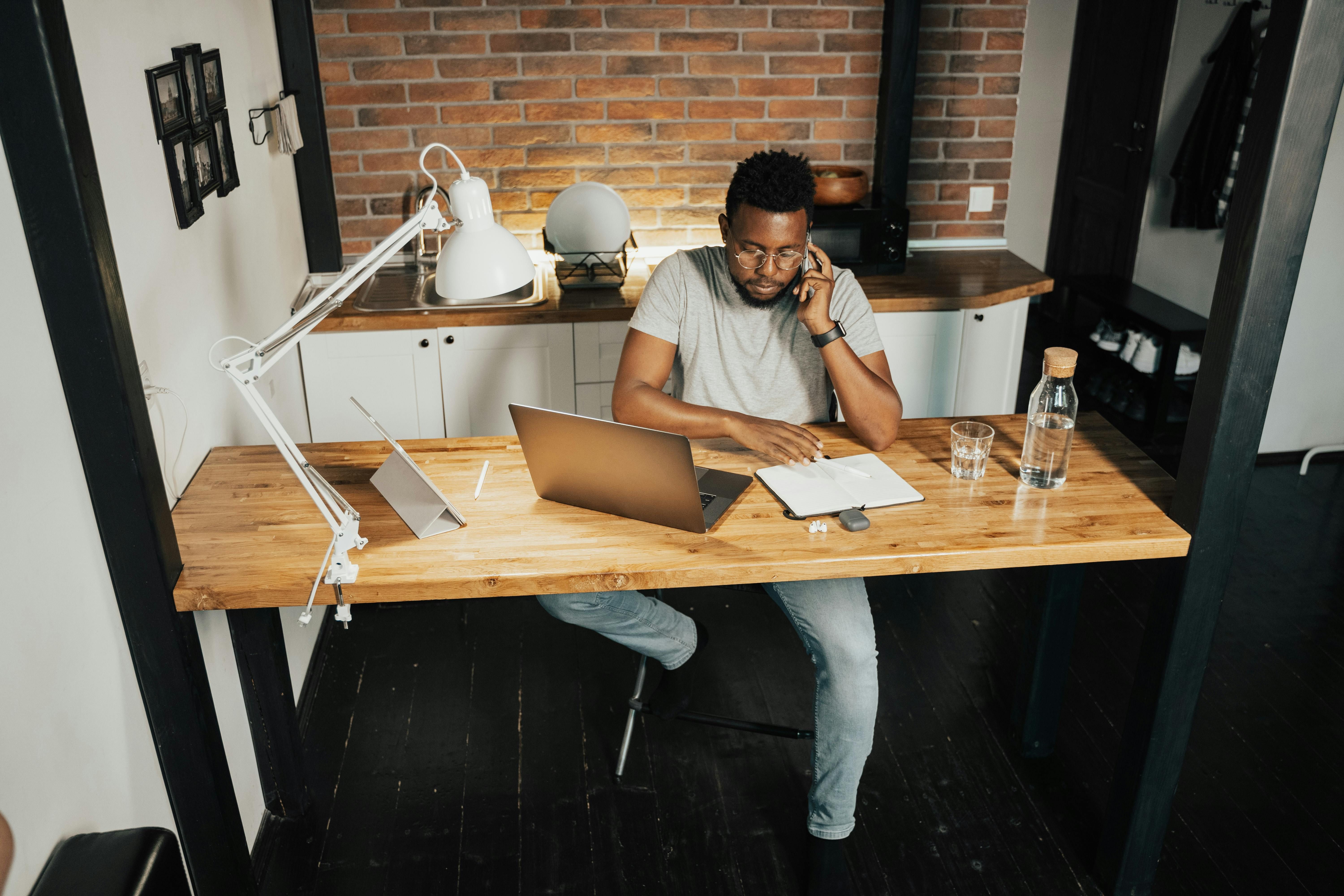 Man sitting at desk with laptop open while taking a phone call