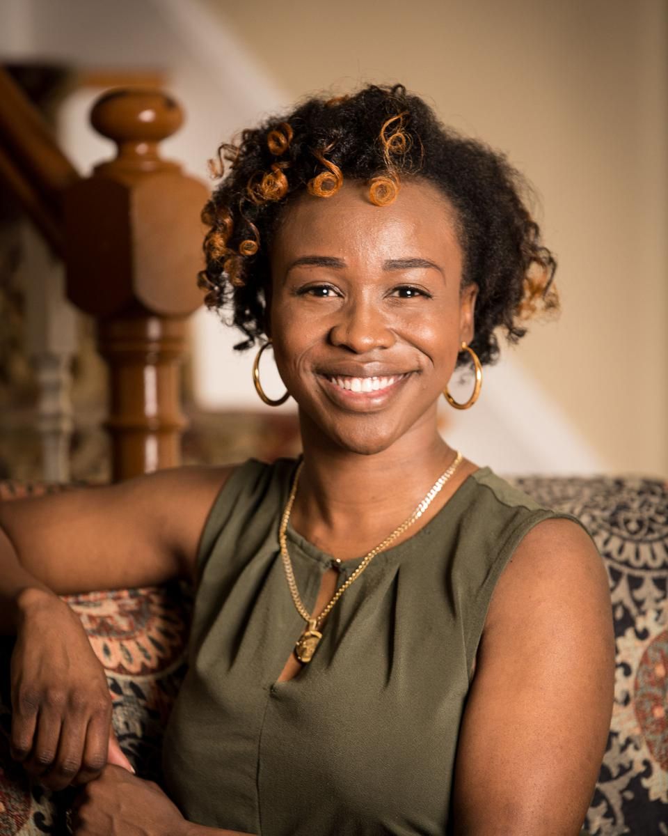 Alma therapist Rode Toussaint leaning up against a polished wood bannister in a light-dappled, homey room.