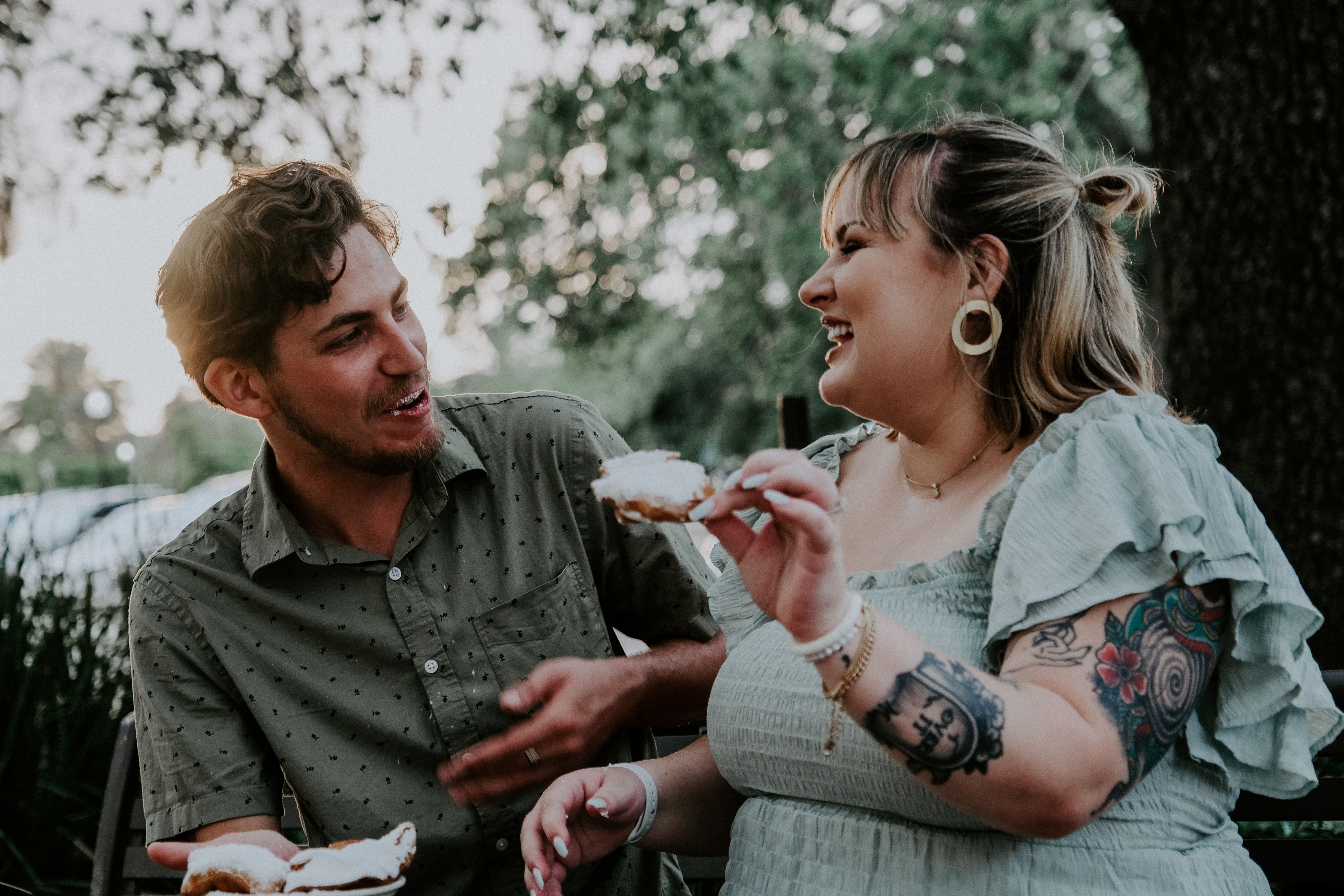 A photograph of two friends who seem to be blissfully disengaged from thinking about food, centered on a snack held in one hand.