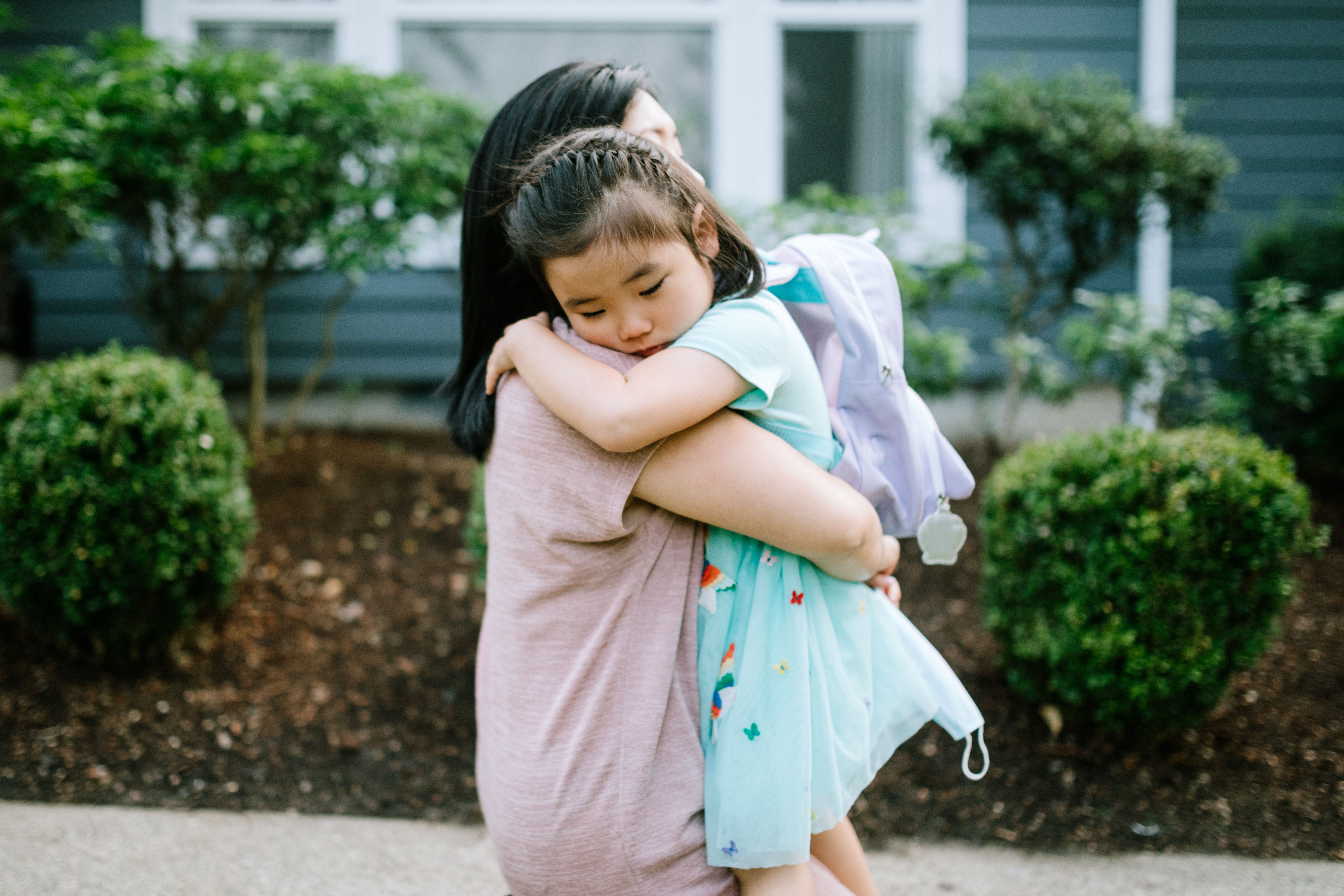 Mother holds sleeping daughter in her arms on a walking path