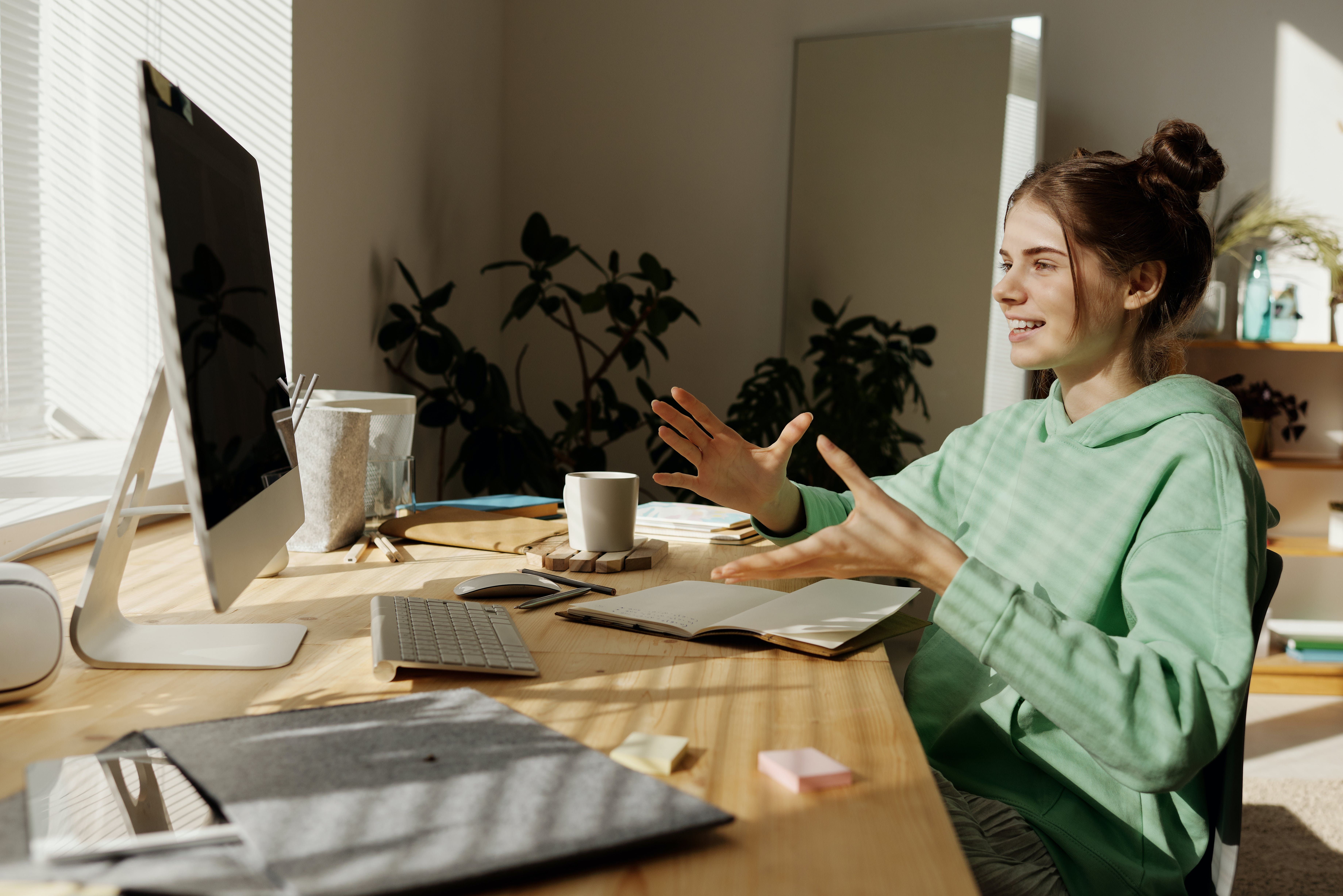 A teenager bathed in sunlight from the window, talking animatedly with her virtual therapist at her computer.