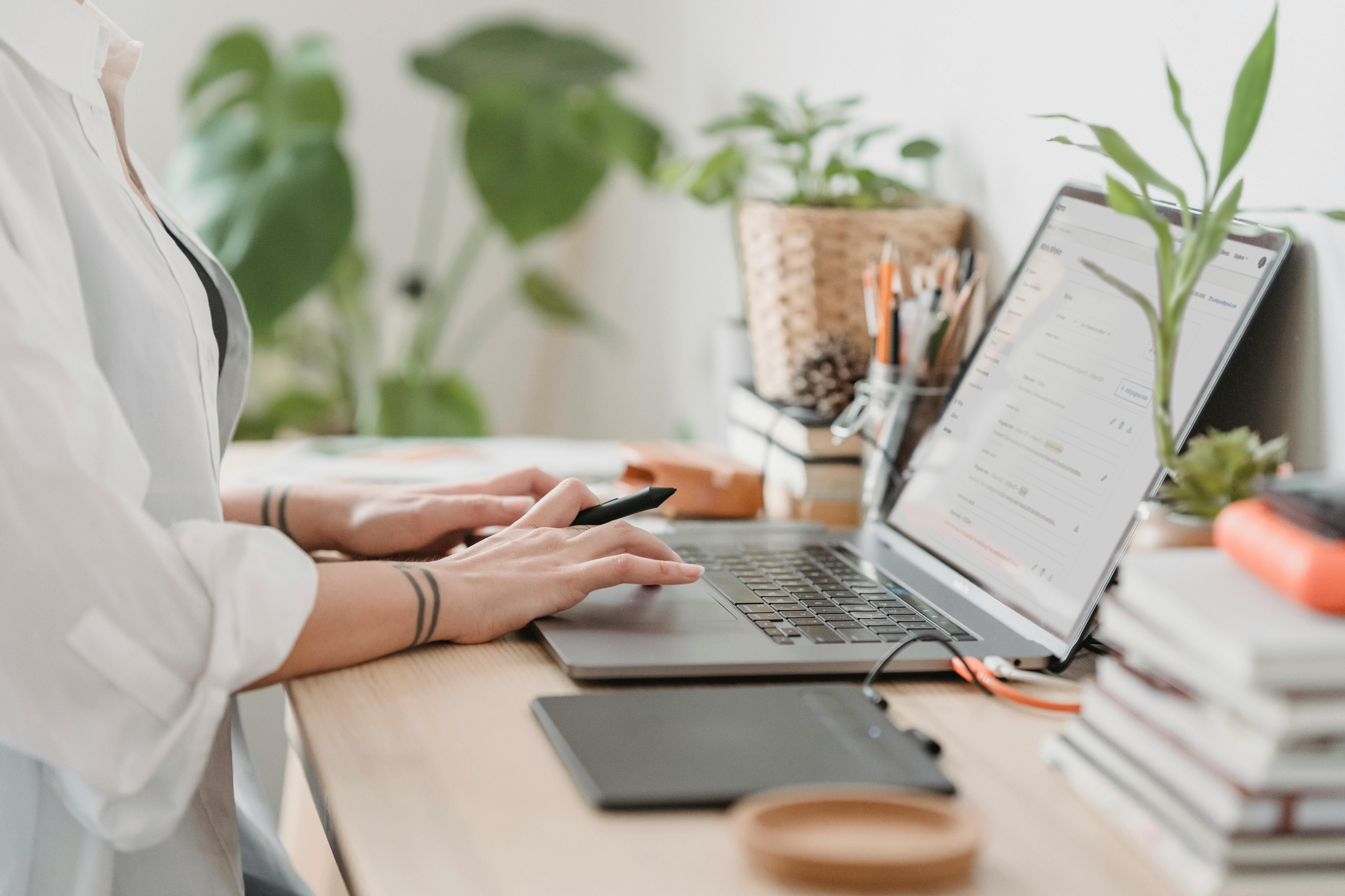 Person with tattooed wrists managing patient information on a laptop