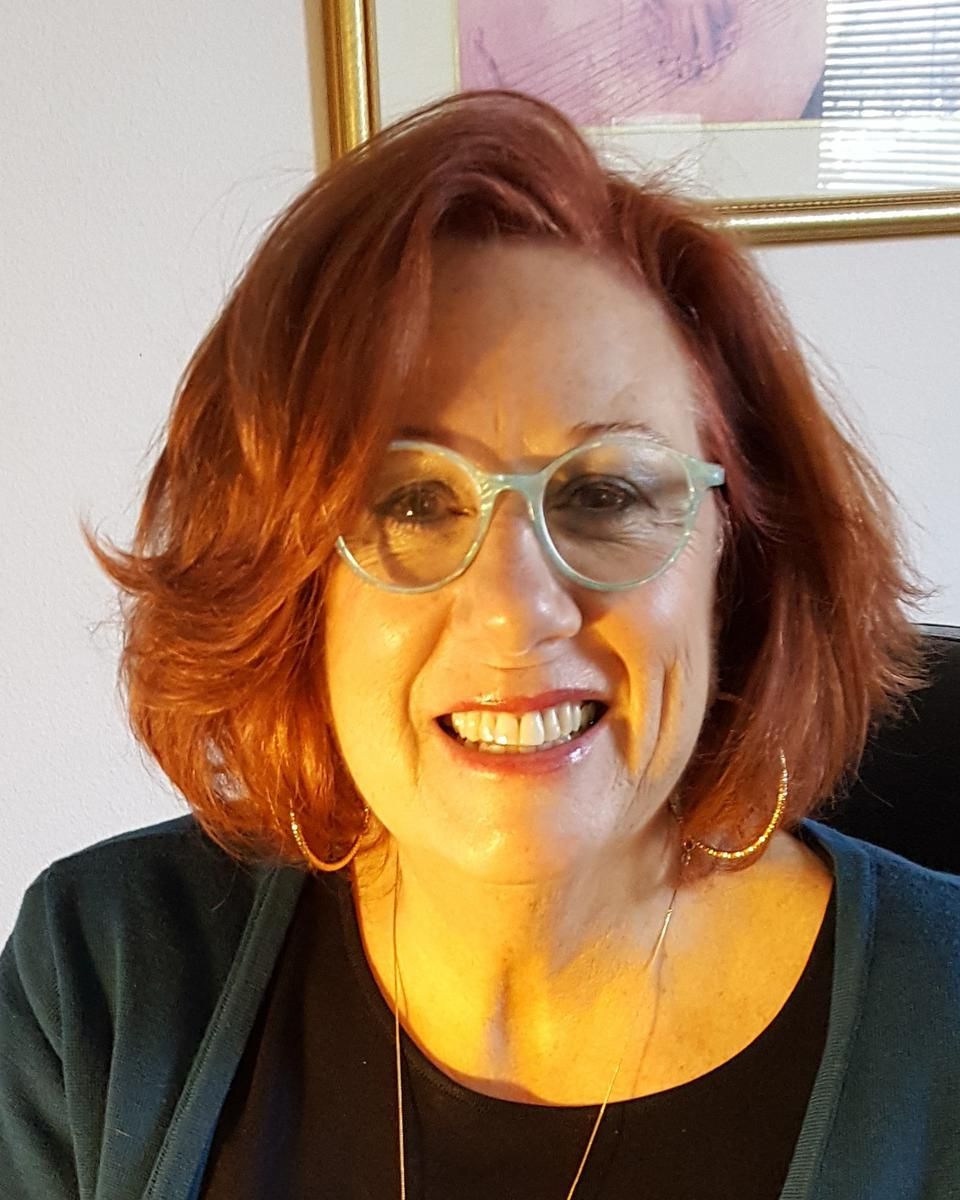 Janet Anselmo-Henson, LPC, smiling to the camera in her therapy office.