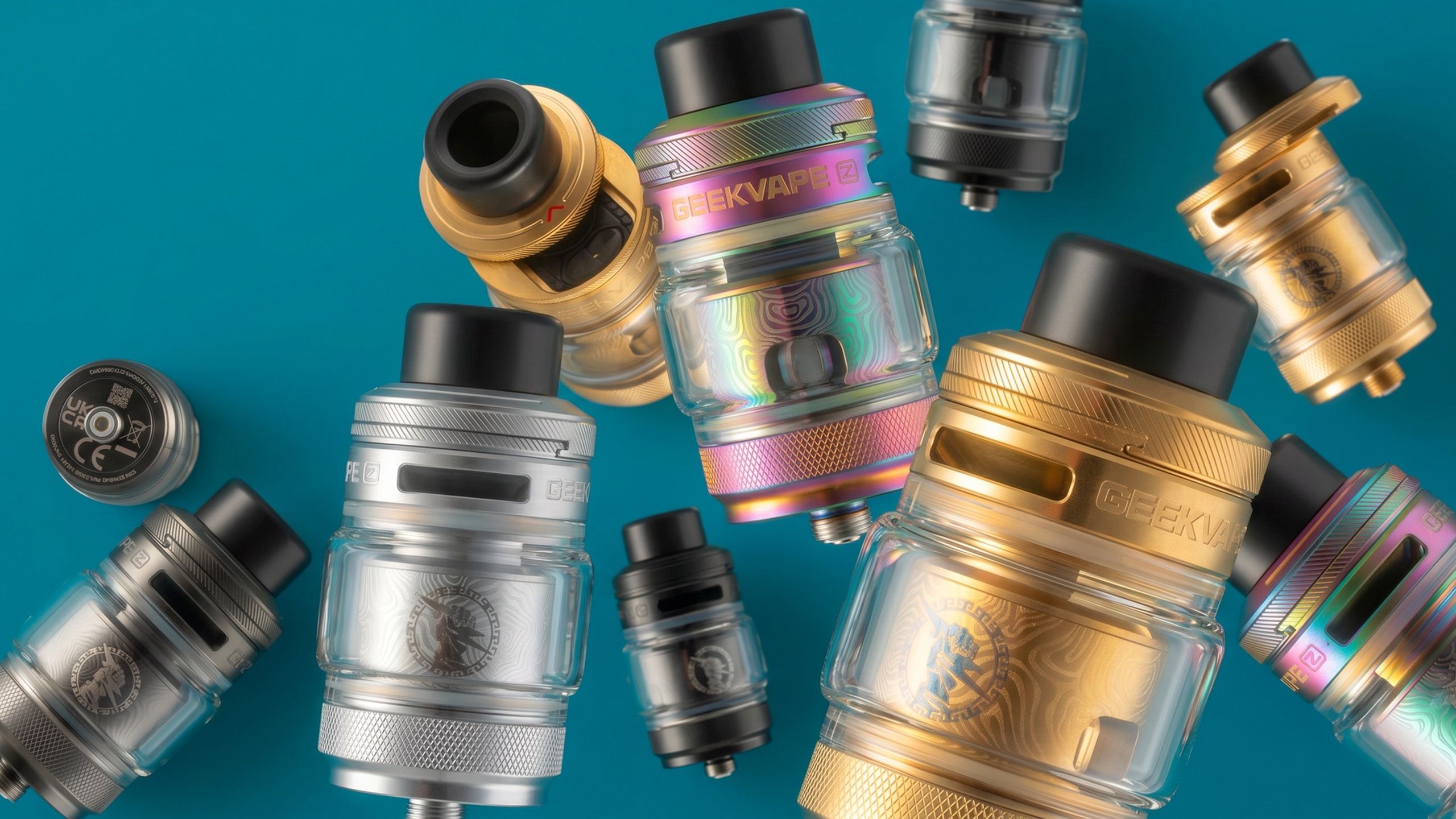 GeekVape Z II tanks — rainbow, gold, and steel finishes scattered across a teal field
