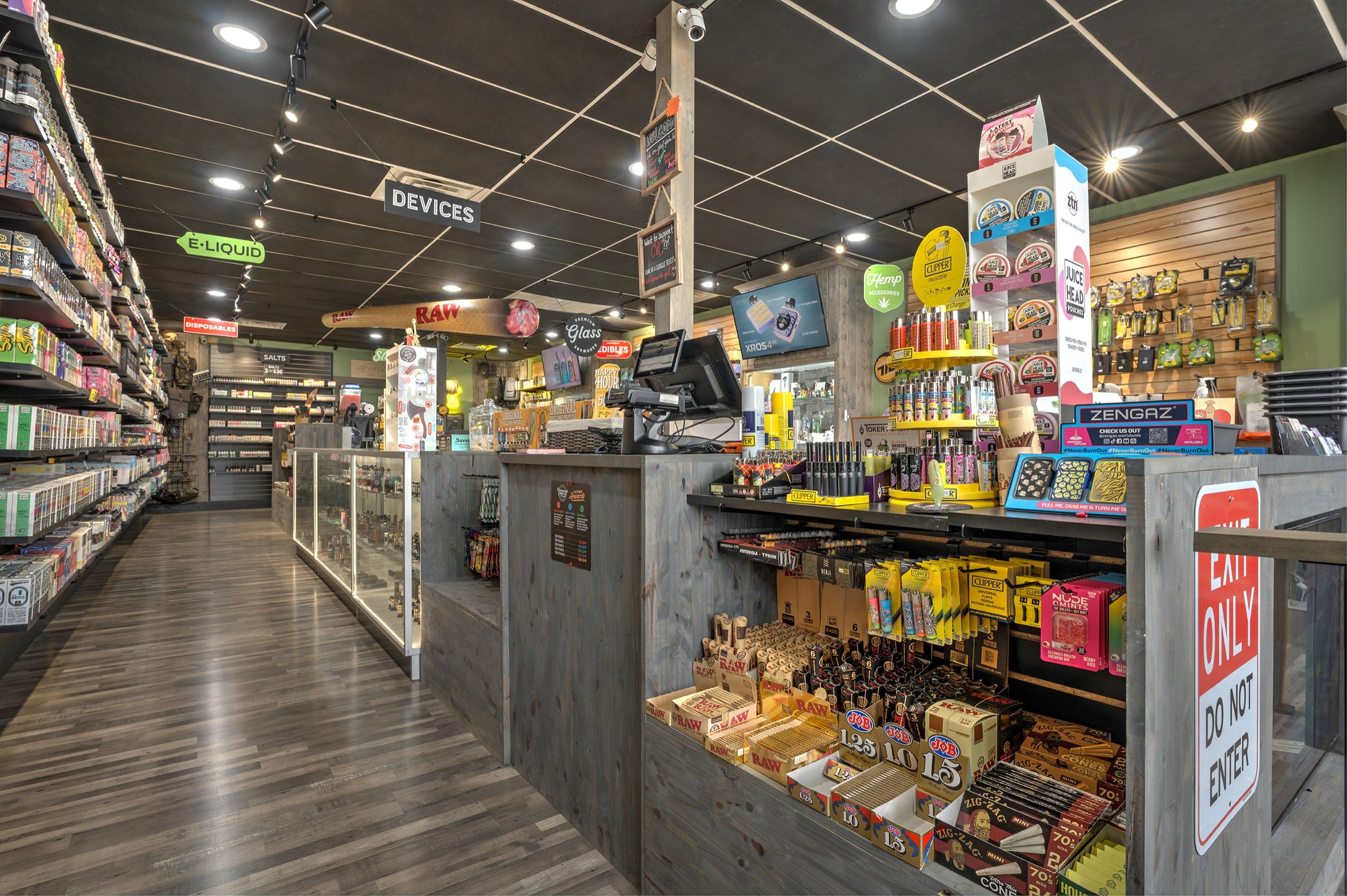 Sales floor toward the register, glass counters and hanging merch under a black ceiling