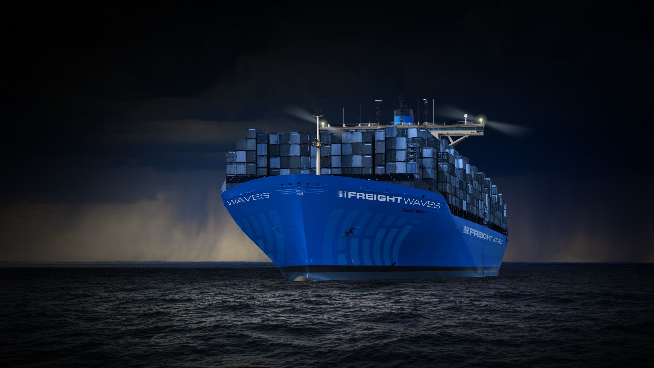 Container ship in FreightWaves blue livery on dark open water at night
