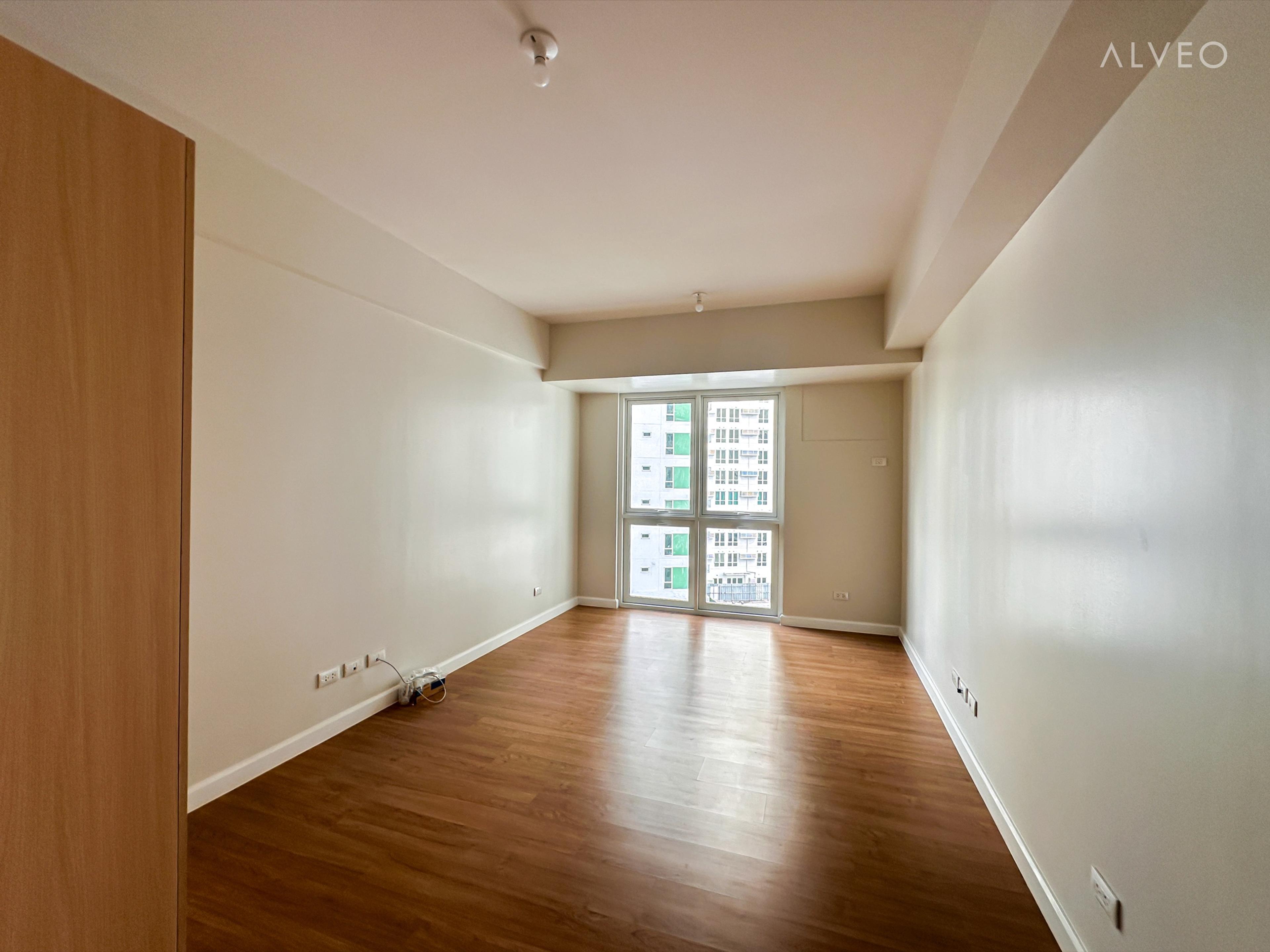 Cerule at Solinea studio unit interior at turnover, with engineered wood flooring and a floor-to-ceiling window overlooking Cebu