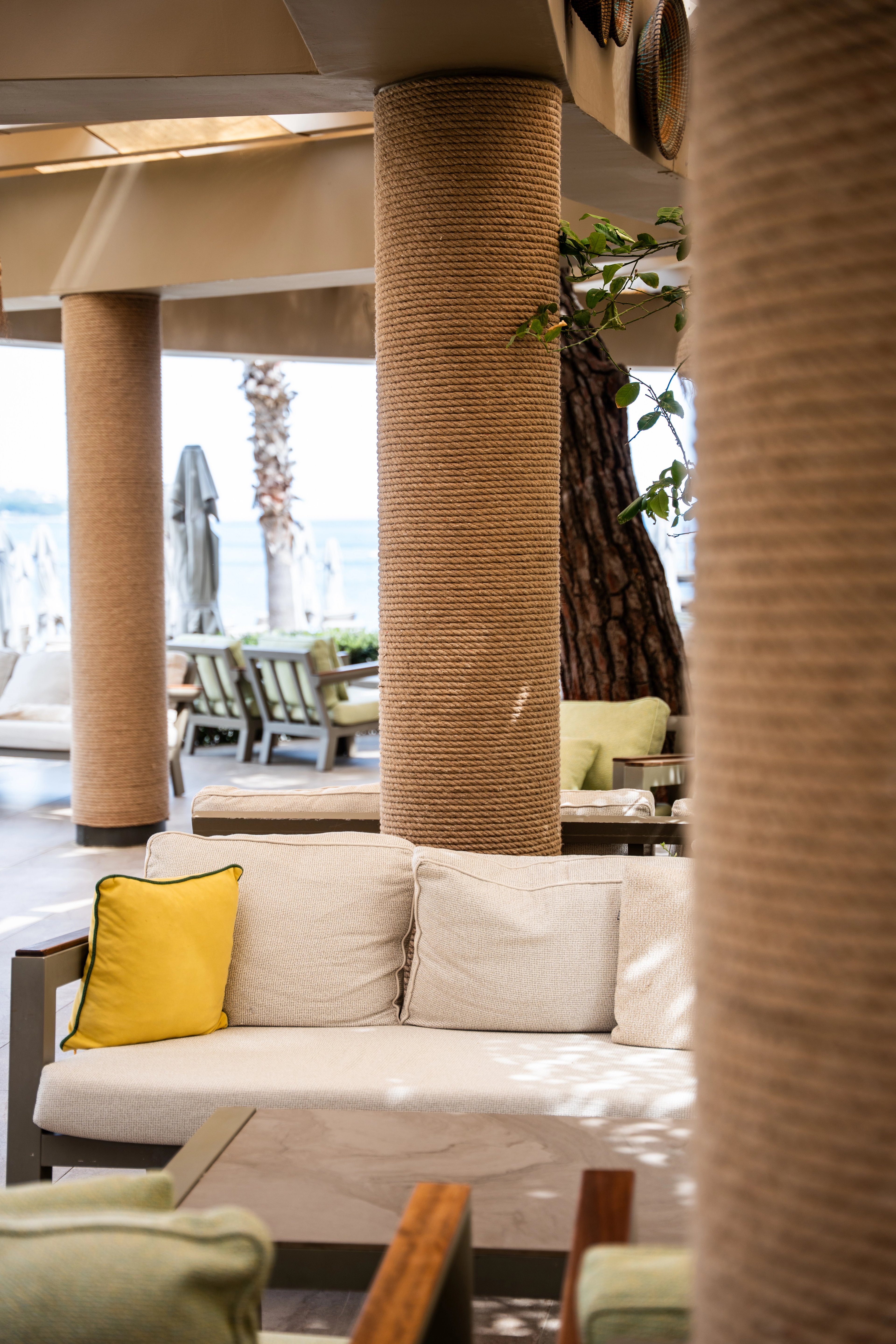 Rope-covered columns beside a pale sofa and low table in a shaded lounge at NG Phaselis Bay.