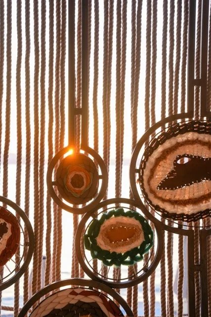 Sunlight passing through vertical strands and circular decorative insets in a screen at So Beach.
