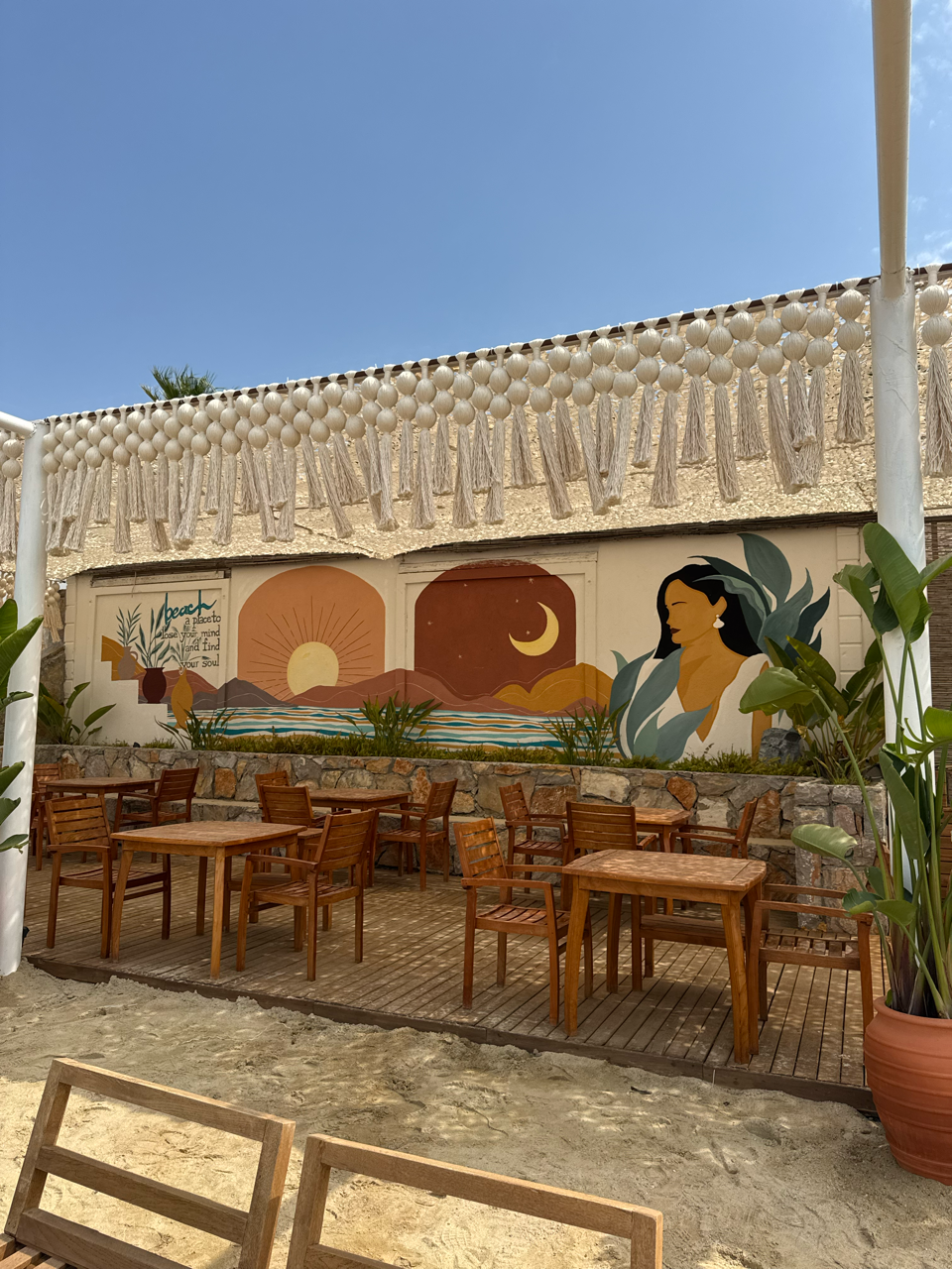 A cream tasseled valance above a painted sunset mural and timber dining tables at TUI Magic Life Bodrum.