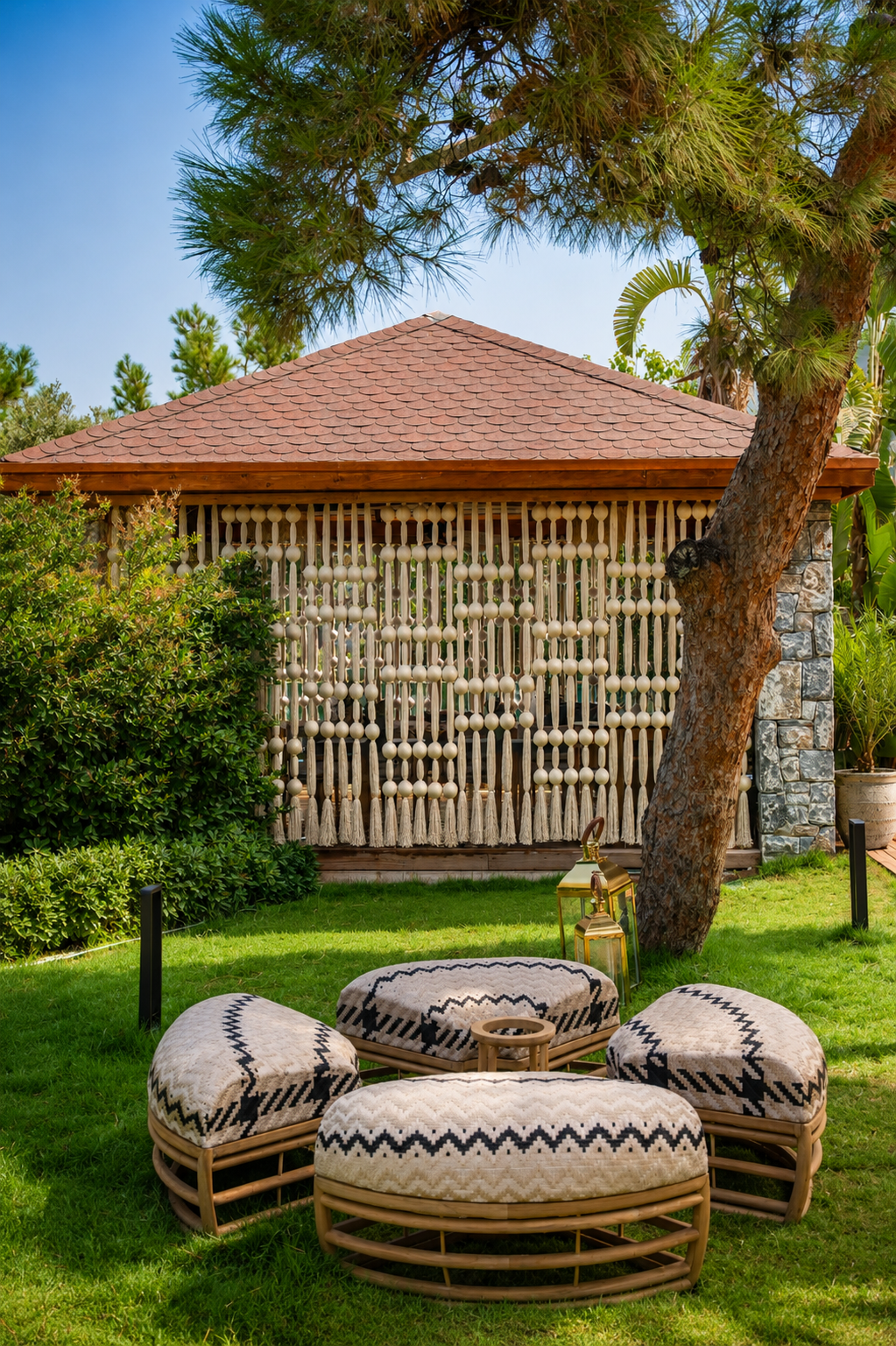 A garden pavilion screened with rows of rounded woven forms, with patterned seating in the foreground at Vogue Hotel Supreme Bodrum.