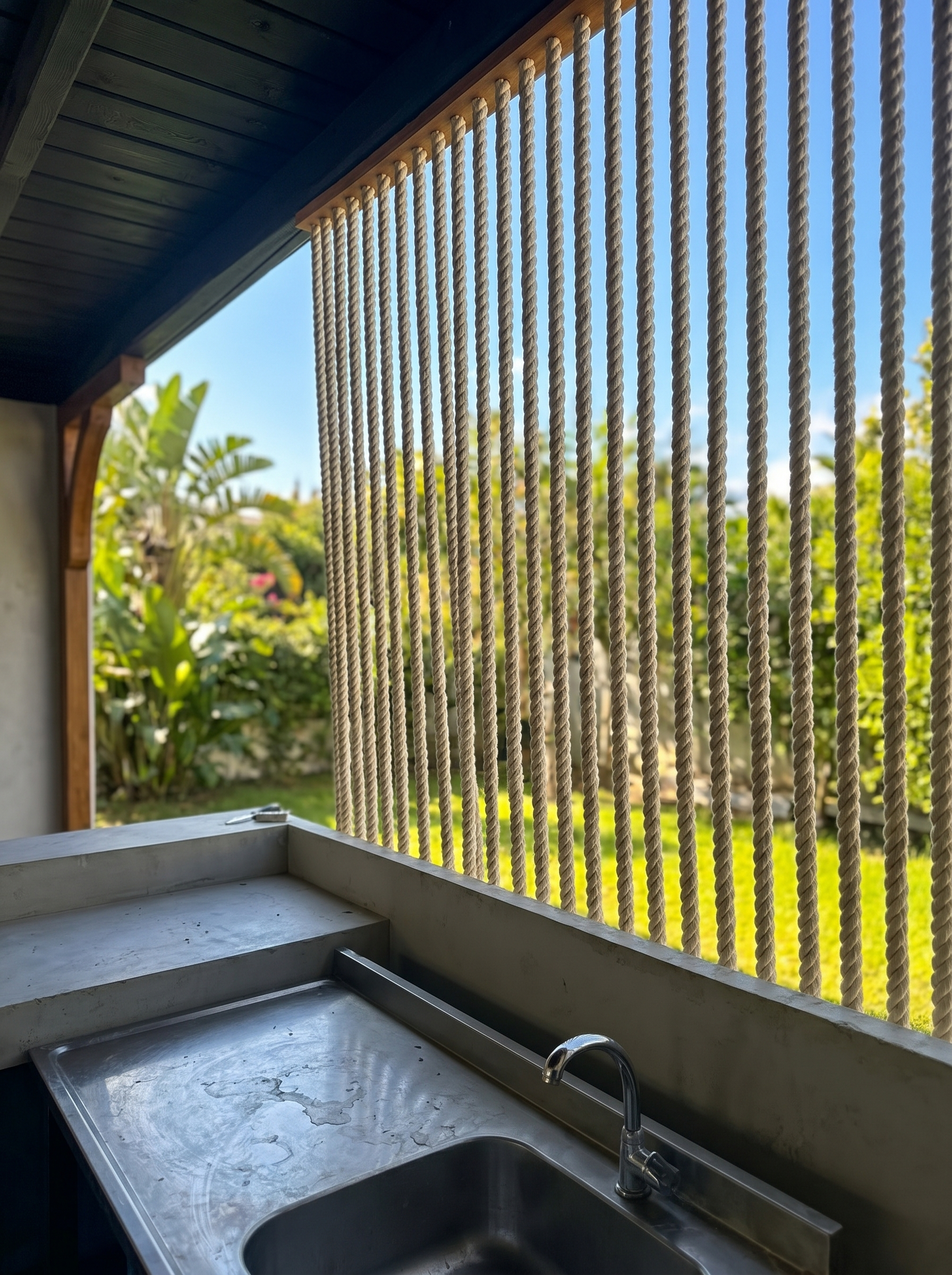 Parallel rope strands across a garden-facing opening above a washbasin at MC Arancia Resort Hotel.