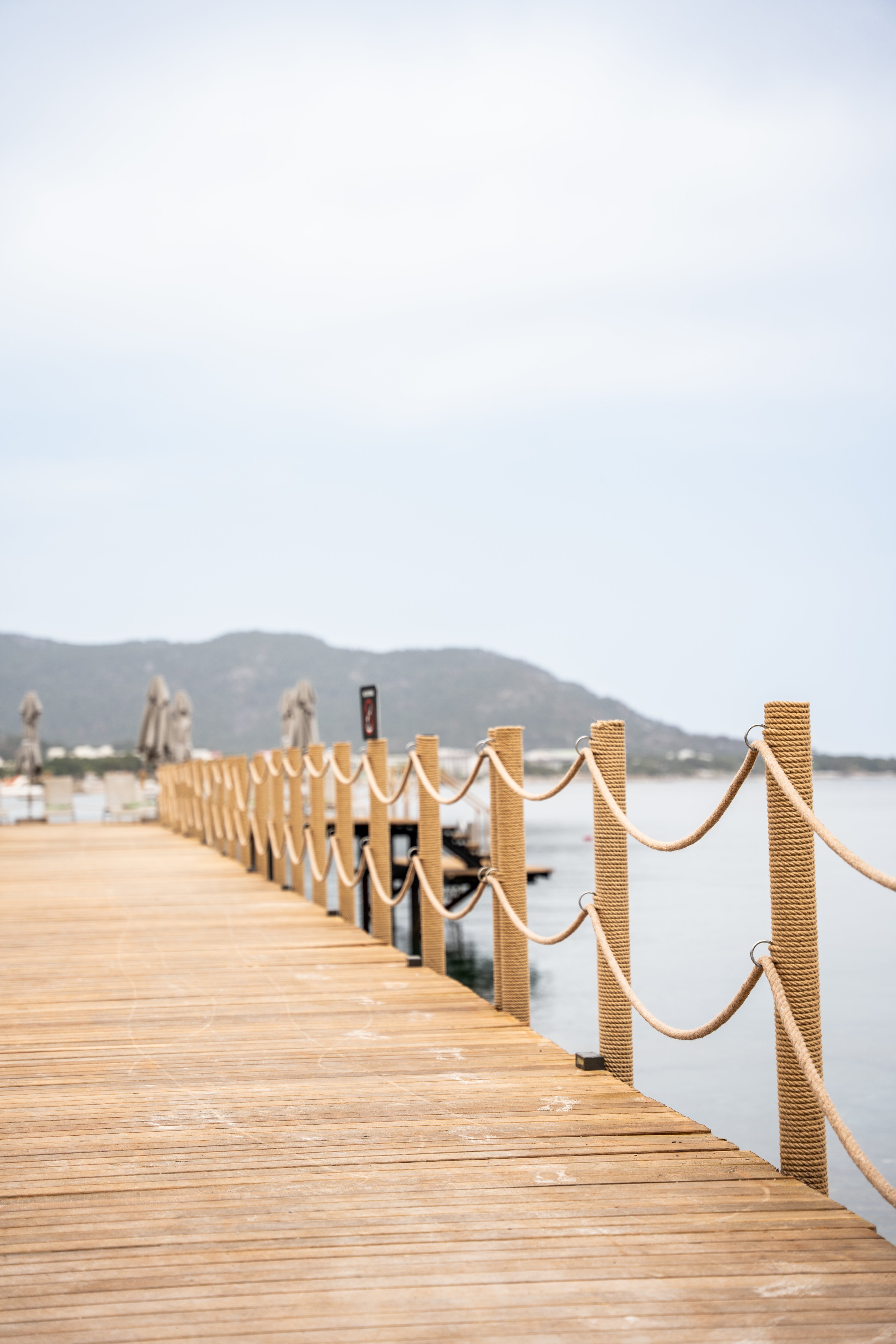 Angled view along the NG Phaselis Bay timber jetty with rope-wrapped posts and draped rope lines, 2025