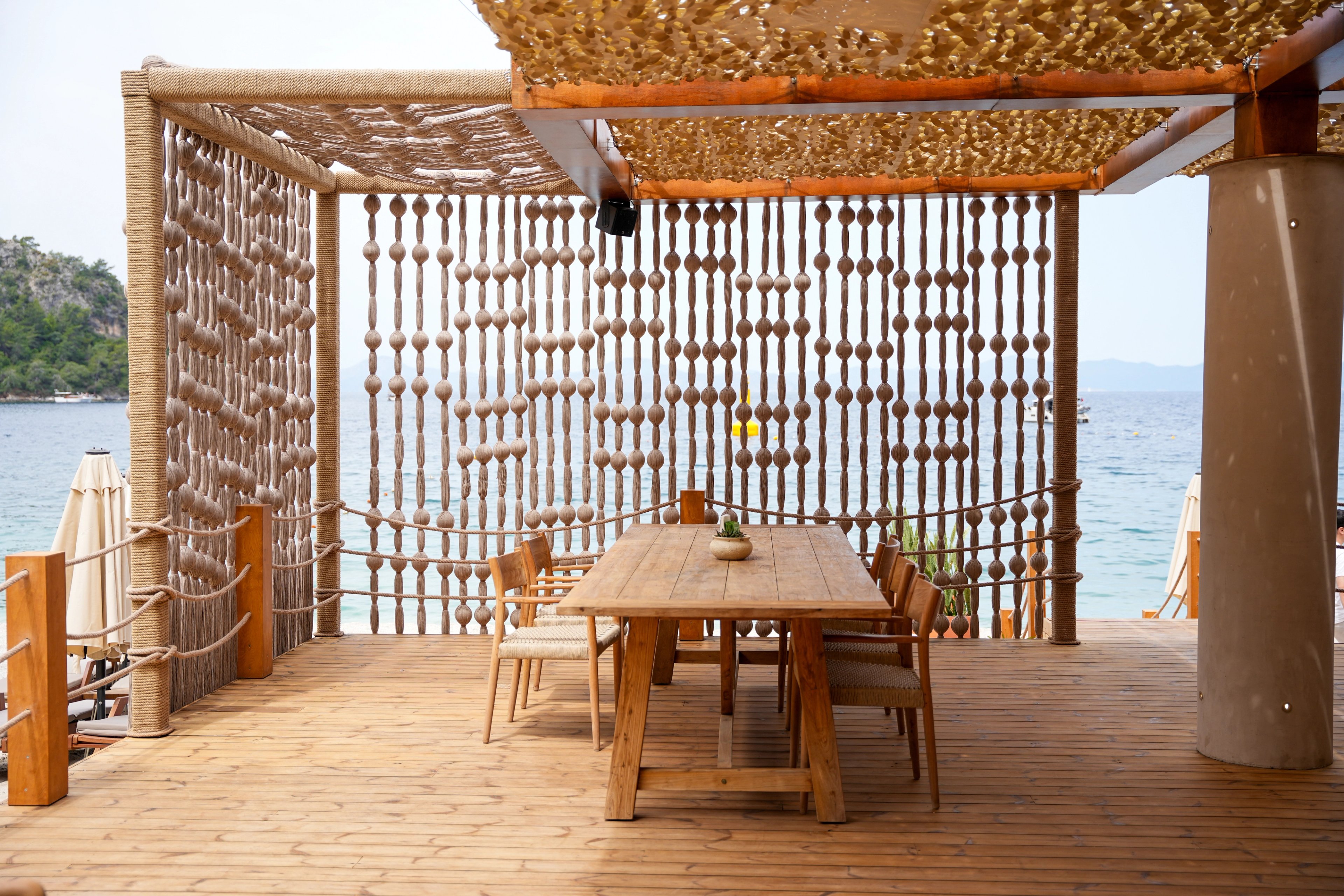 Rope-covered framing and a screen of rounded textile forms around a waterfront dining table at So Beach.