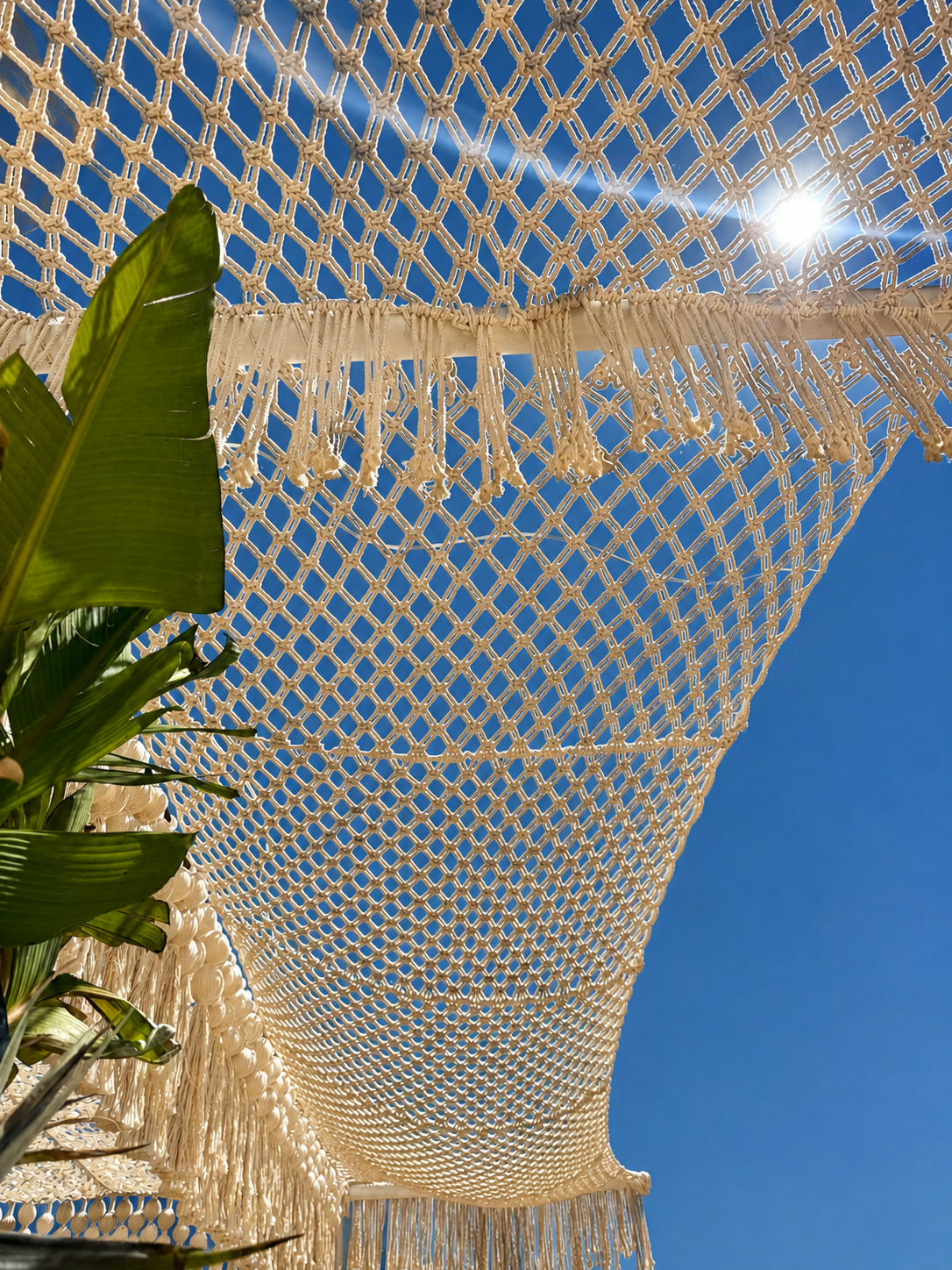 Sunlight shining through a cream knotted net canopy and hanging fringe against blue sky at TUI Magic Life Bodrum.