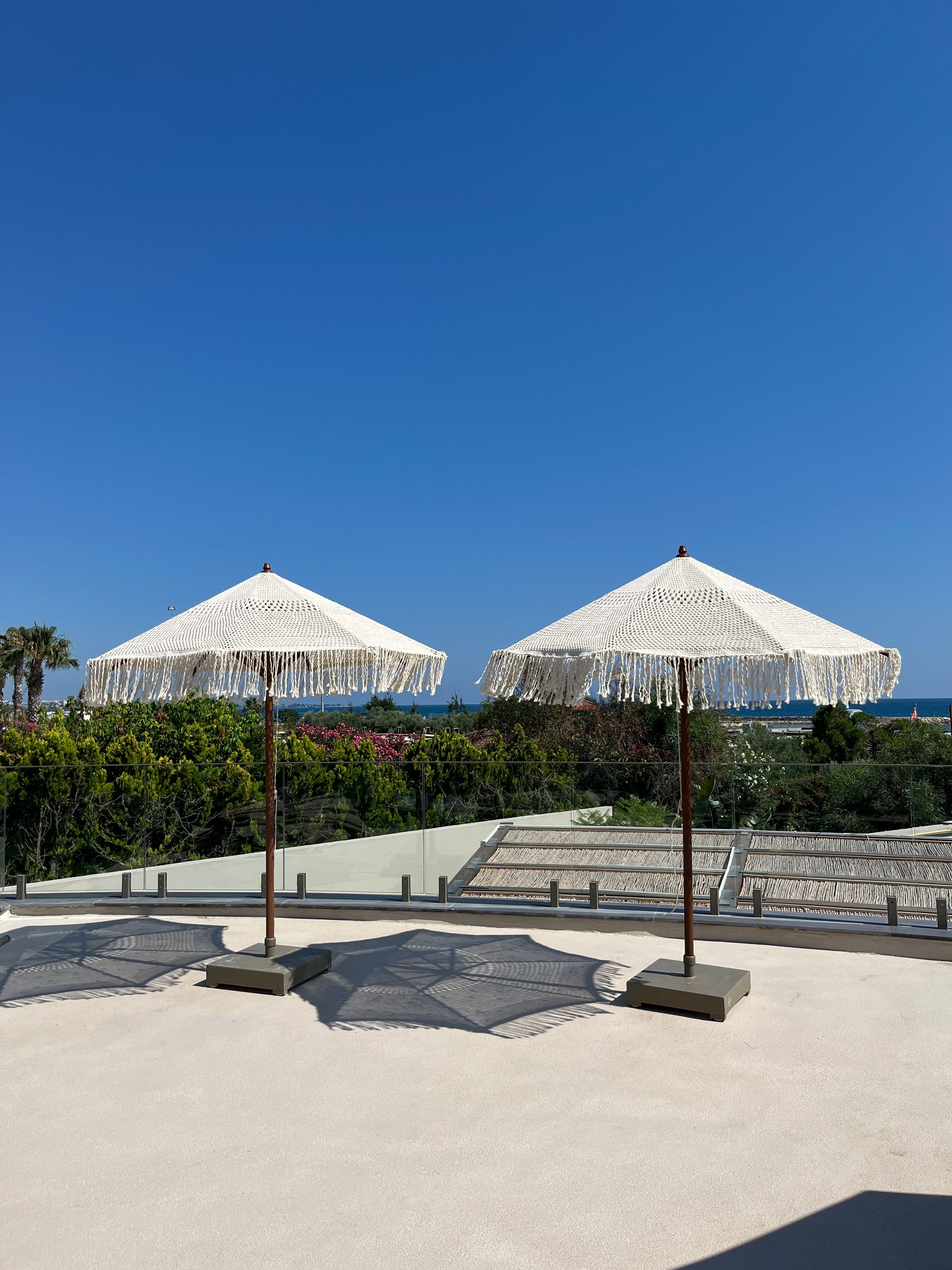 Macramé parasols on the Dimare four-wheel mobile base on a resort terrace above the sea