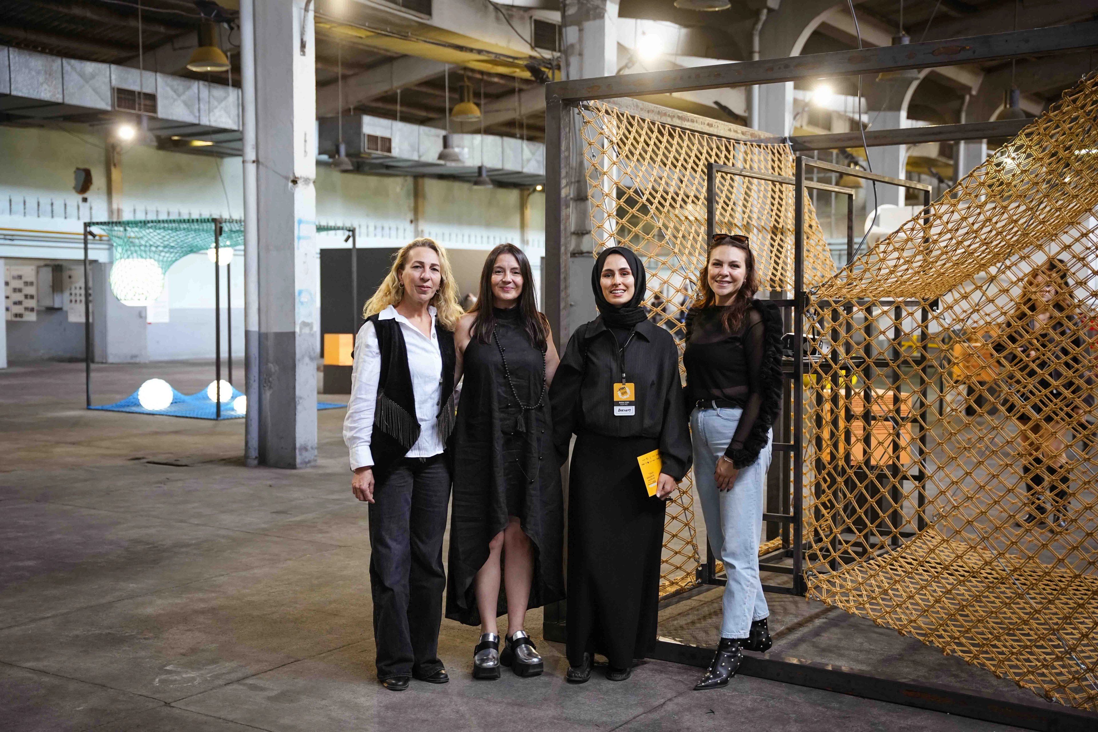 Four people standing beside a yellow rope-net installation, with a teal installation behind them at IABA 2025.