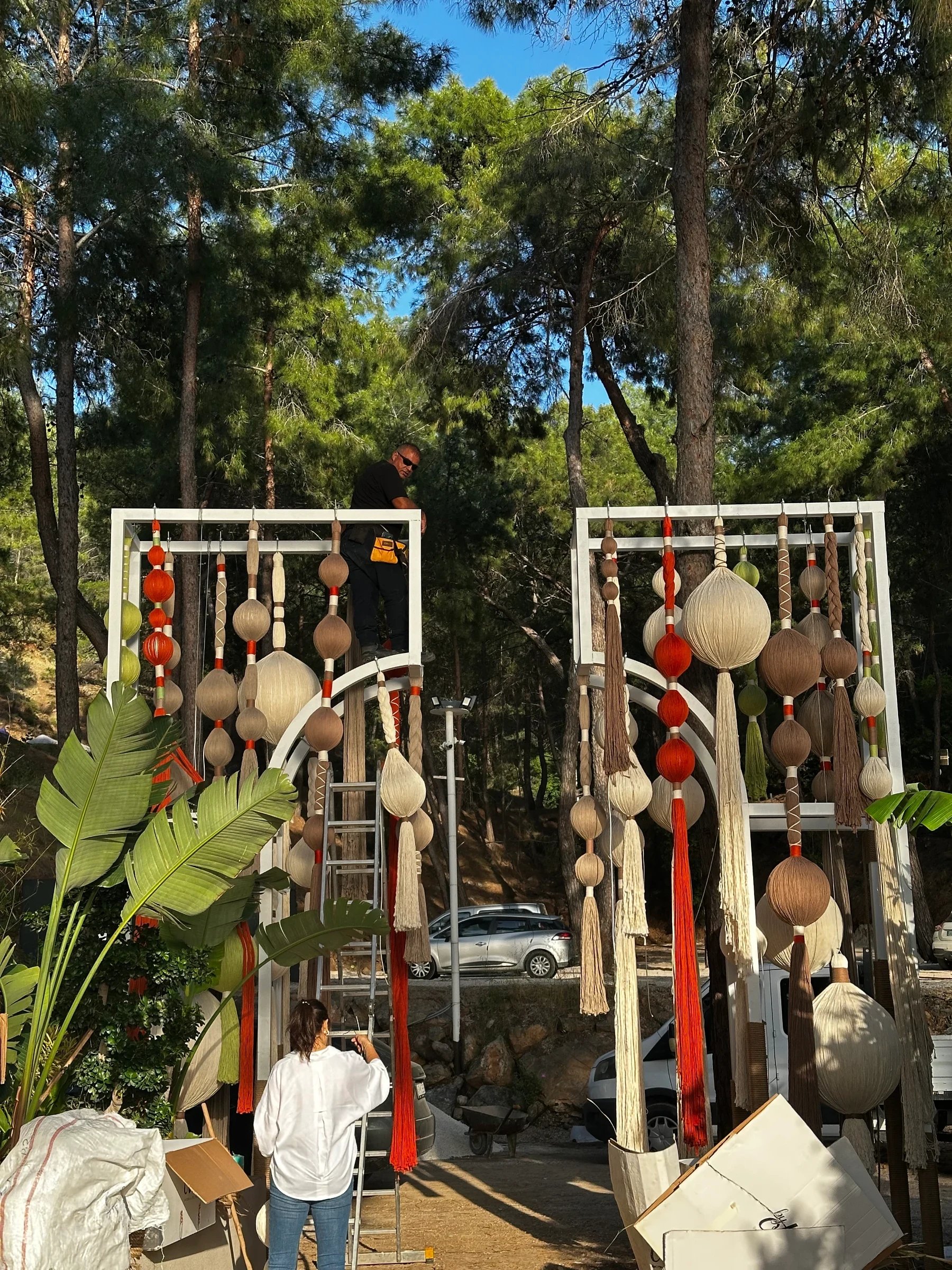 People fitting tall decorative frames with suspended rounded forms and coloured fringe.