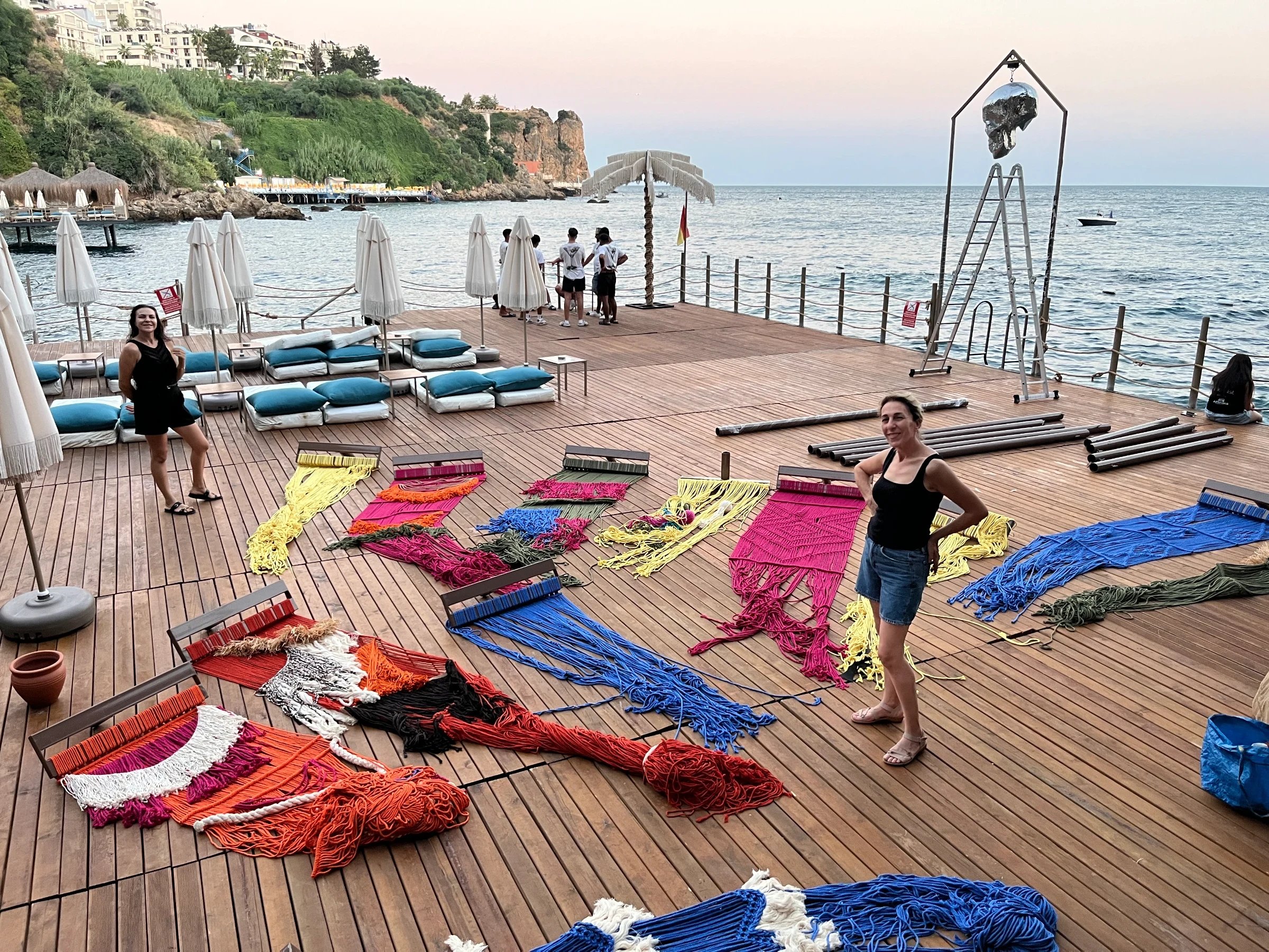 Brightly coloured fringed panels laid out across a waterfront deck.