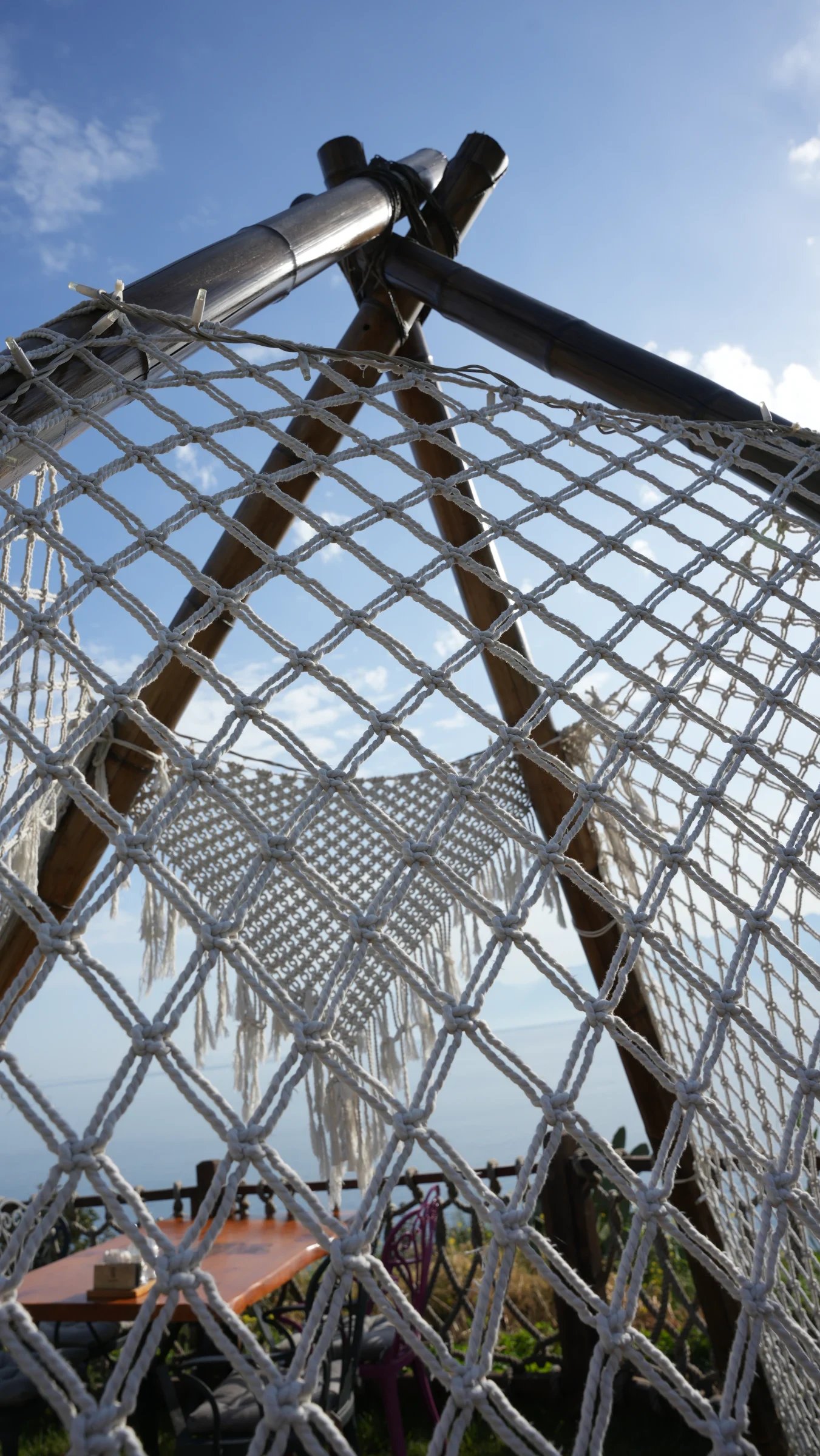 A fringed Dimare macramé panel seen through the knotted netting of the garden A-frame at Lucky Monkey Hotel