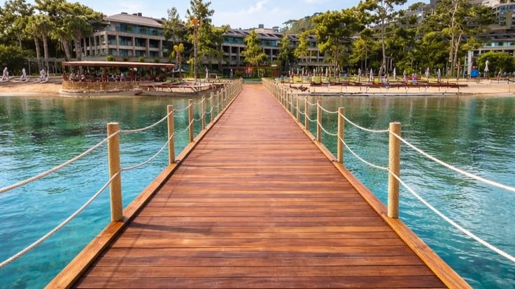 A timber jetty bordered by rope rails and rope-wrapped posts leading toward the shore at NG Phaselis Bay in 2026.