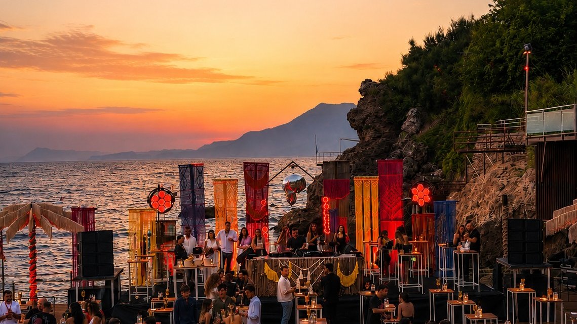 Dimare hand-knotted crimson fibre-art banner columns lining the cliff-top stage at Bilem Beach above the sea at sunset