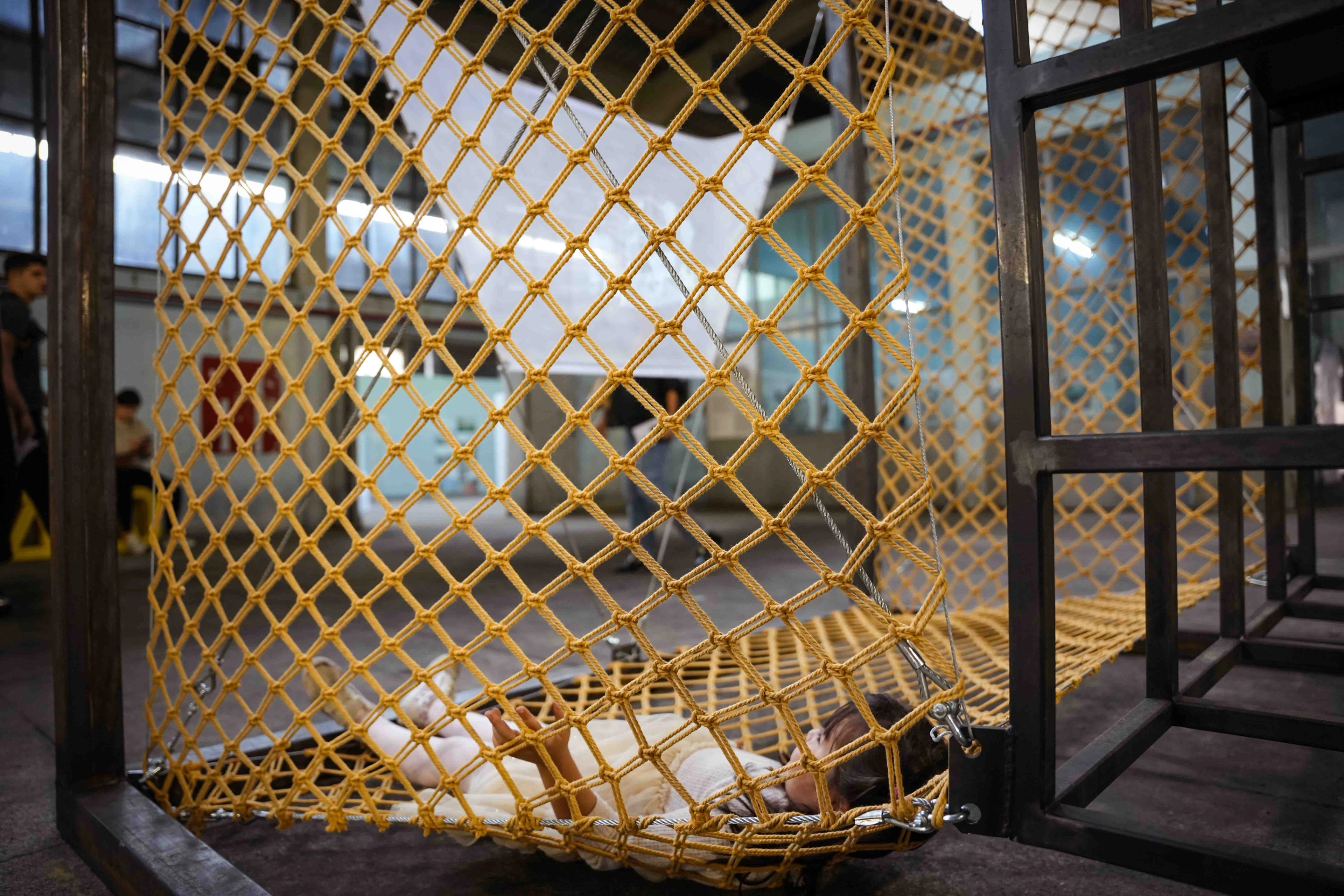 Close view of yellow knotted netting hanging inside a dark rectangular frame at IABA 2025.
