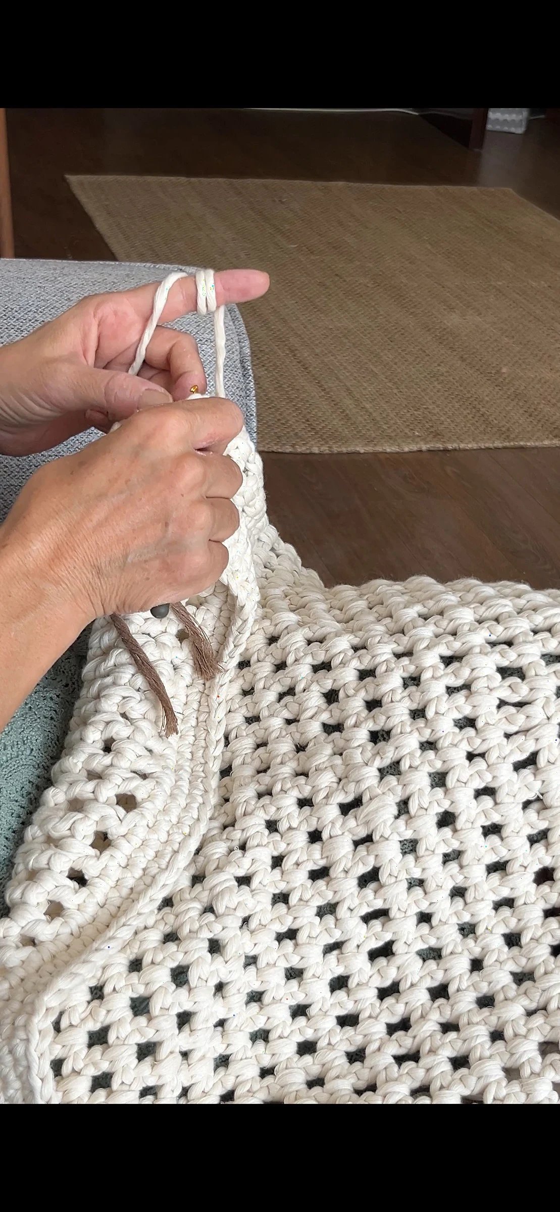 Hands working cream yarn with a crochet hook.