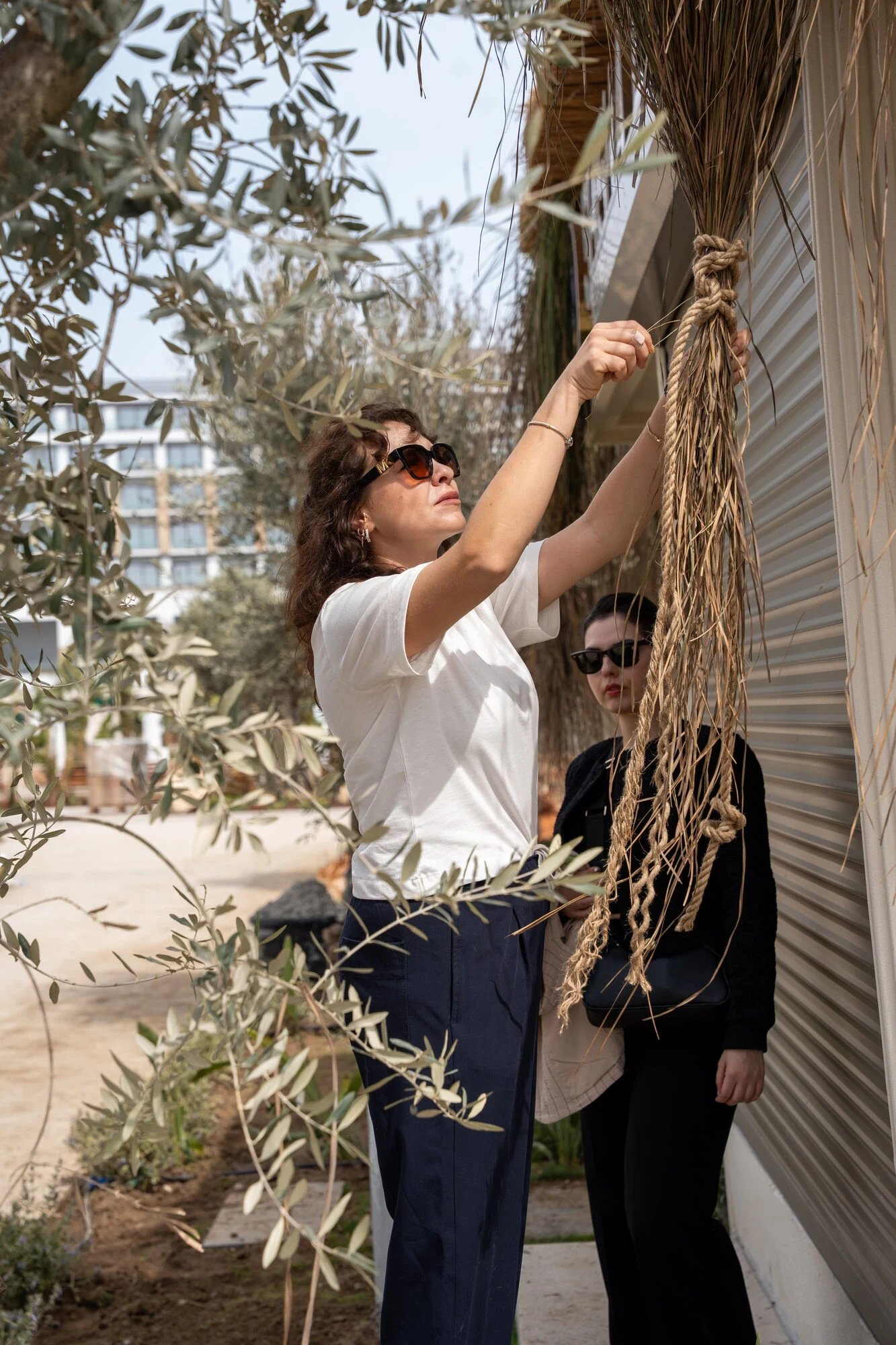An artisan tying thick rope strands beneath an outdoor timber frame.