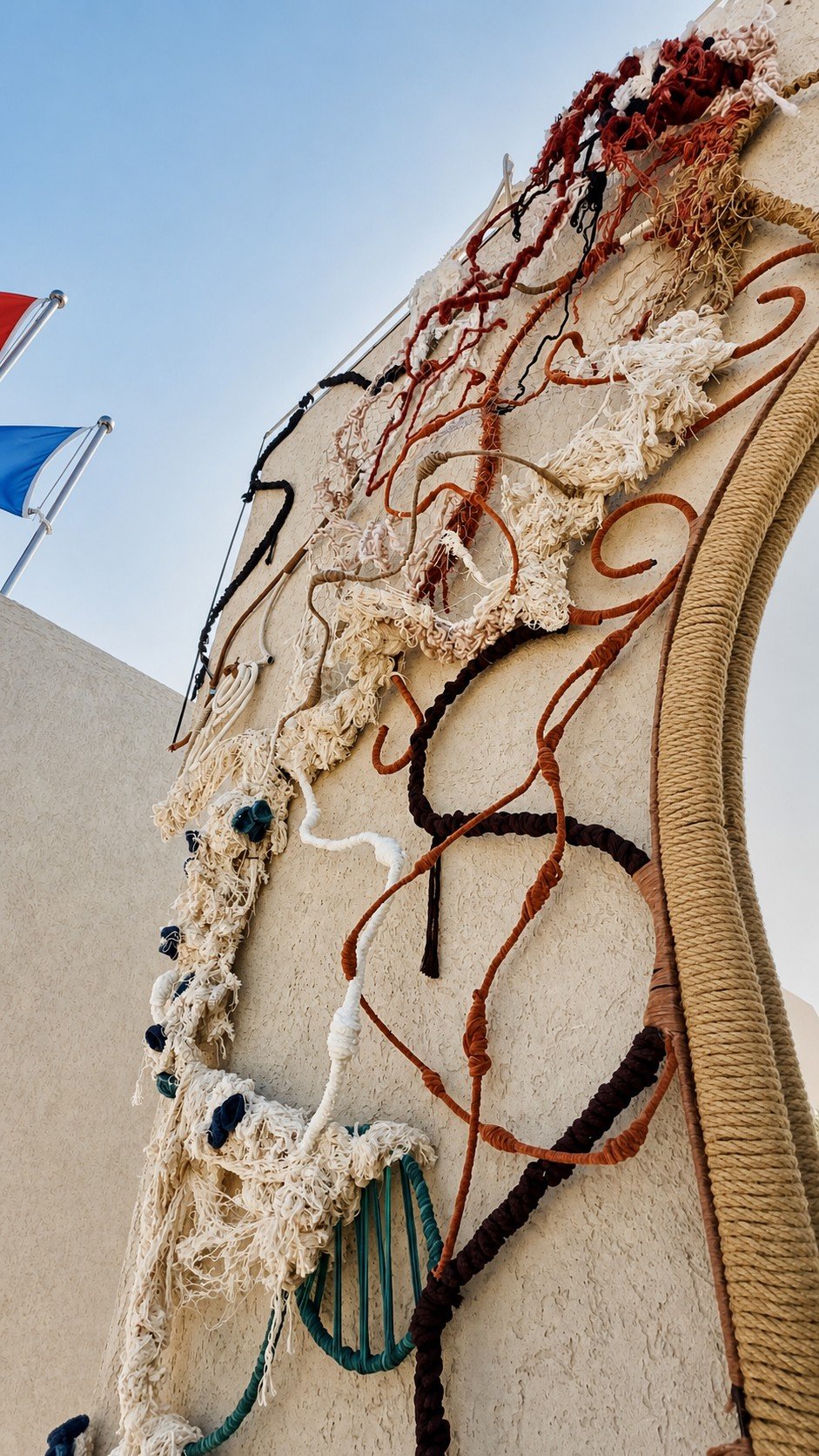 Close view of freeform cream fibres and coloured rope lines beside a round mirror on a textured wall at Adalya Bliss.