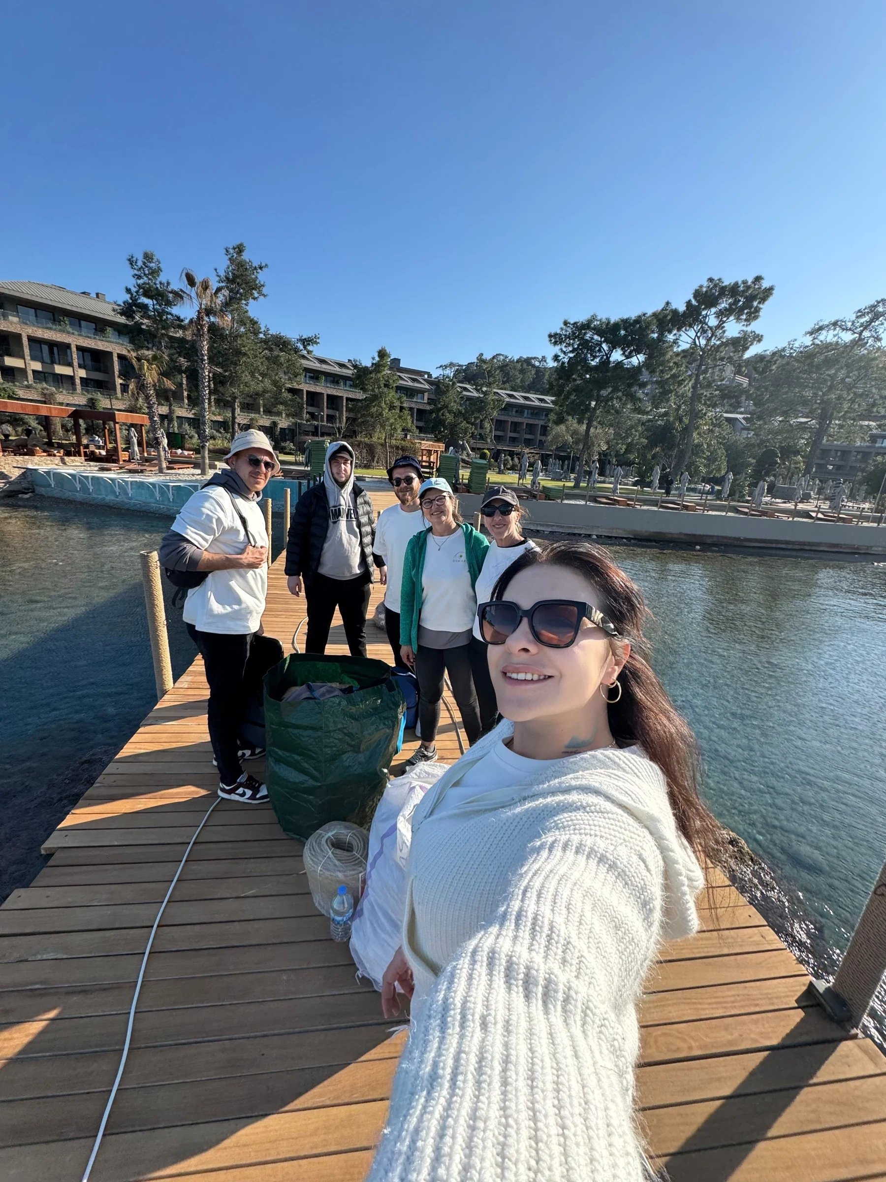 A group photographed together on a wooden waterfront jetty.