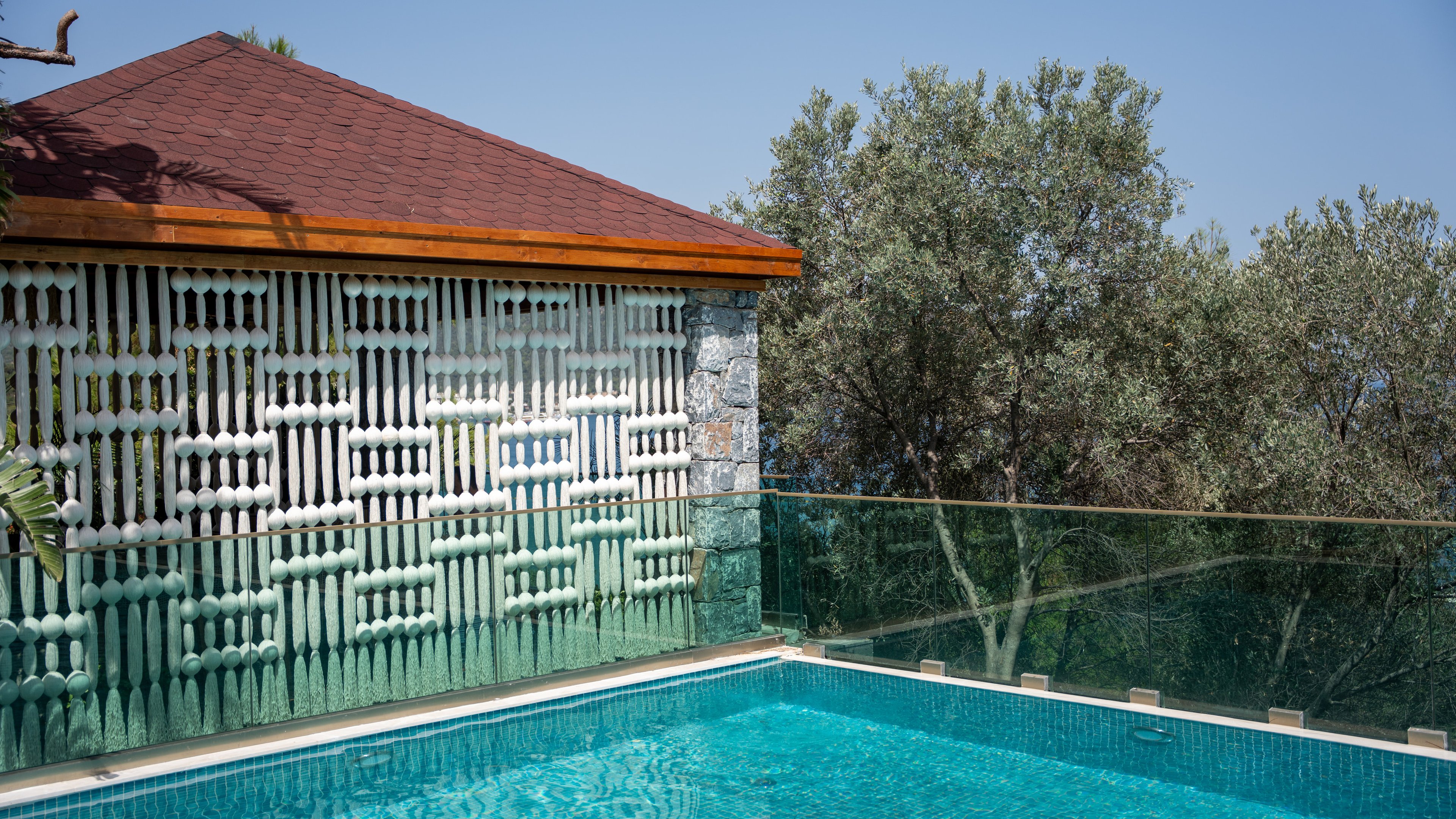 A cream patterned screen reflected in the turquoise pool beside a pavilion at Vogue Hotel Supreme Bodrum.