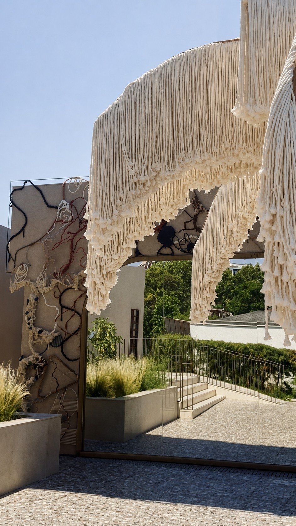 A decorative rope-and-fibre mirror wall reflecting the entrance path, with cream palm fringe above at Adalya Bliss.