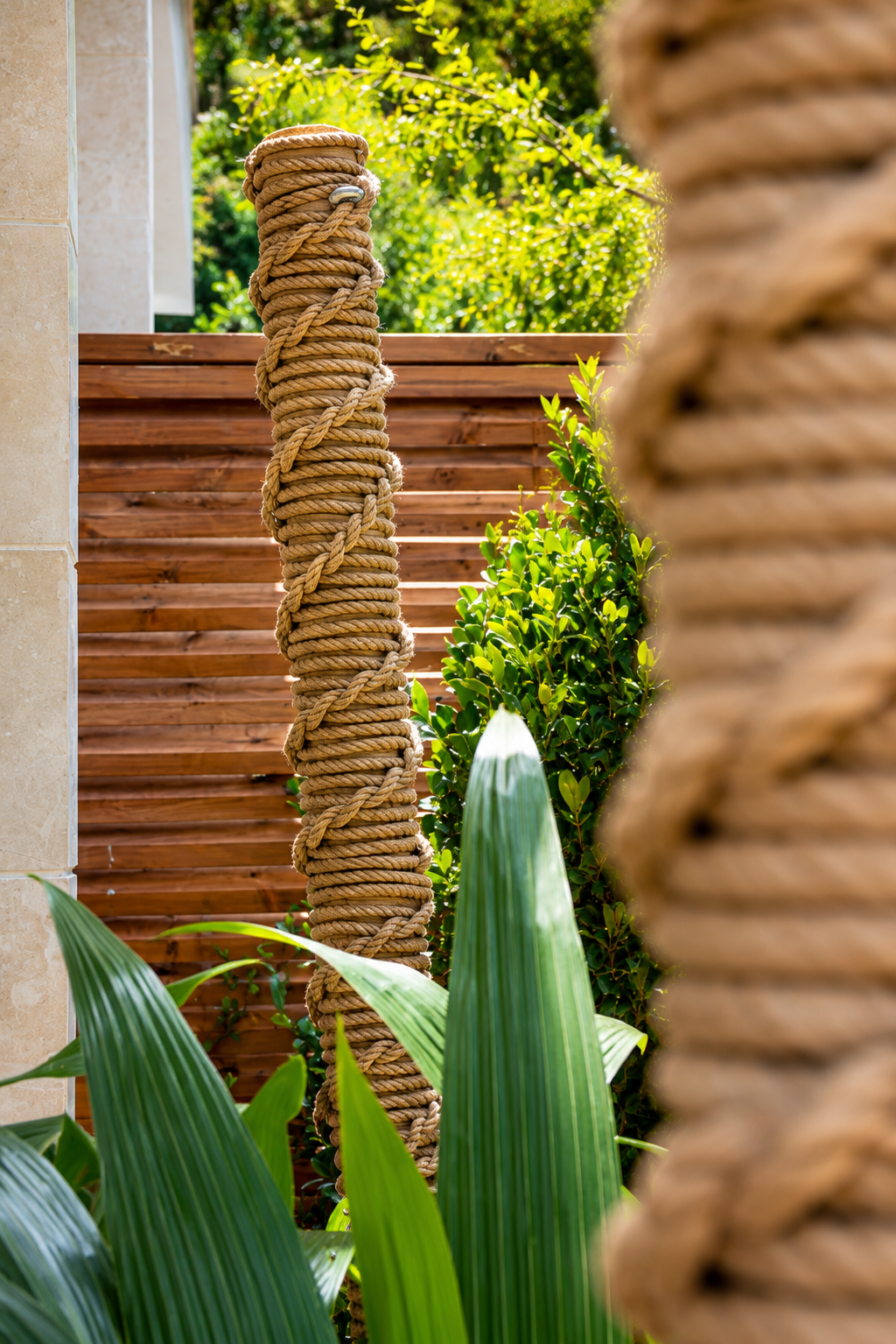 Close perspective of rope-wrapped posts, with a timber screen and green foliage at Vogue Hotel Supreme Bodrum.