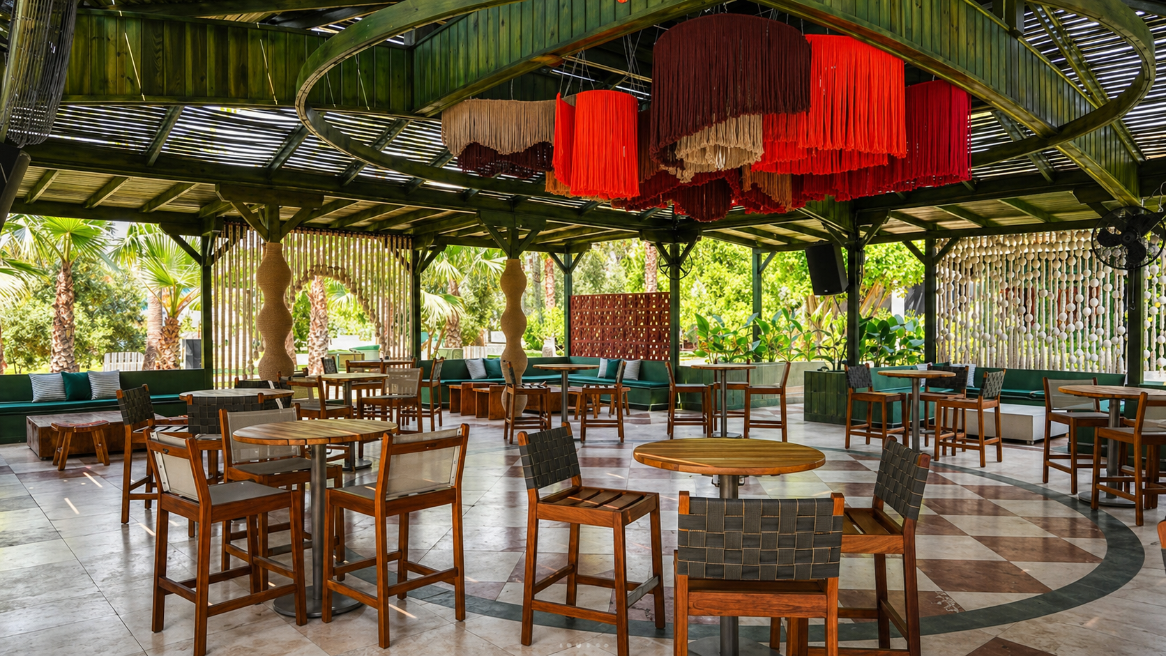 Suspended red, burgundy and neutral fringe forms above tables in an open-sided restaurant pavilion at MC Arancia Resort Hotel.