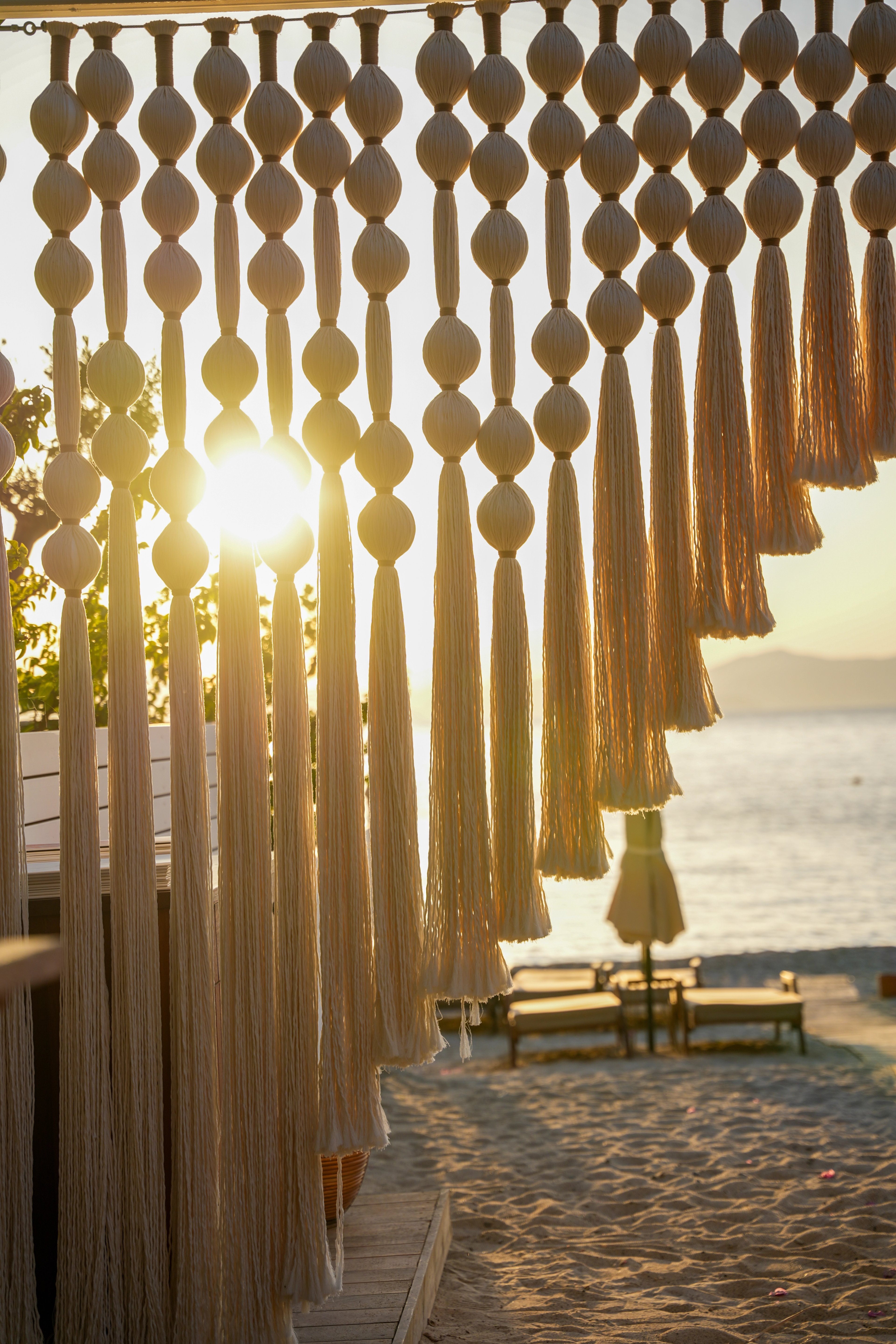 Close view of a cream sphere-and-tassel screen silhouetted against the sea at sunset at So Beach.