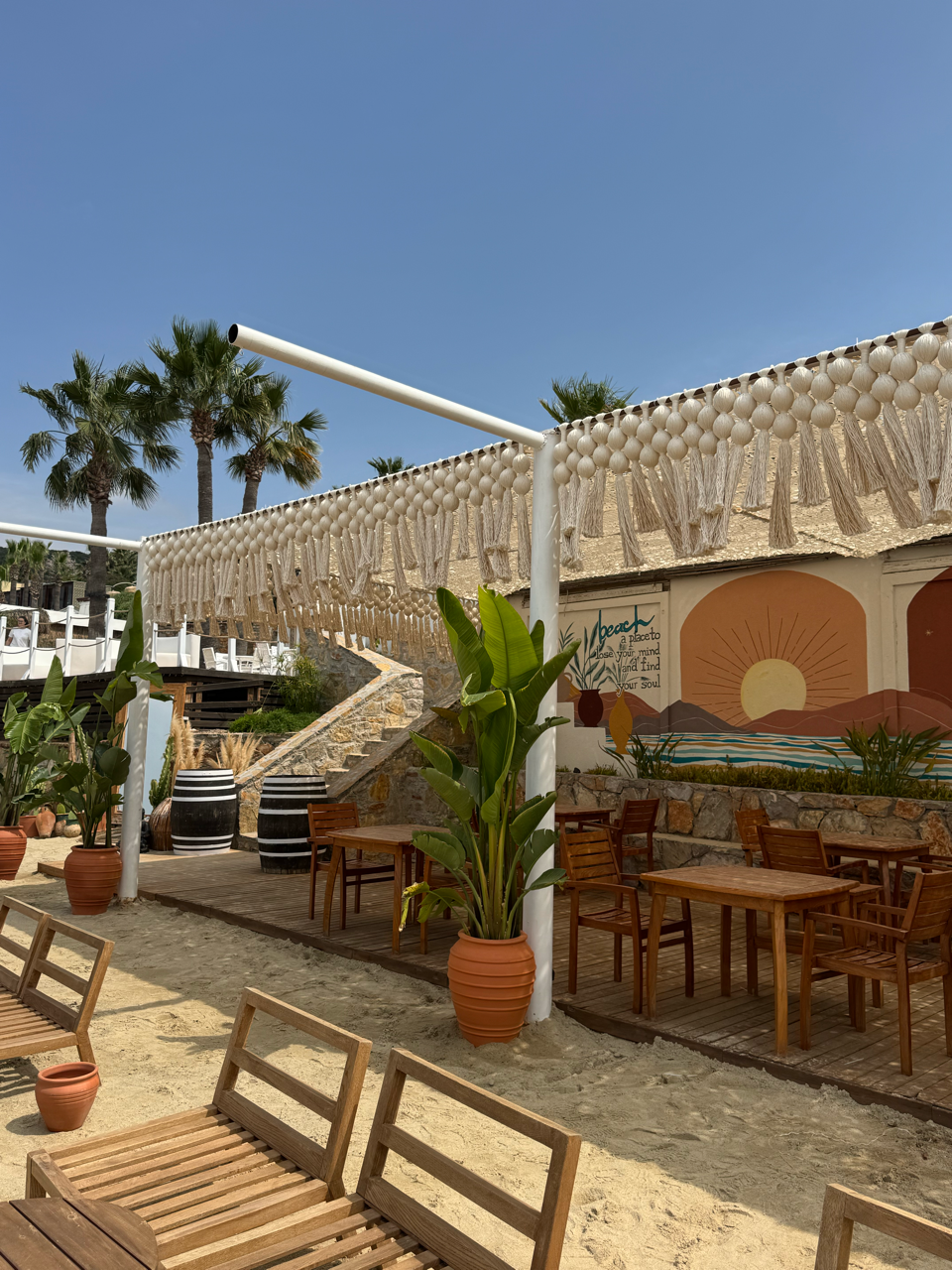 A long cream valance of rounded forms and tassels above a terrace mural, tables and potted plants at TUI Magic Life Bodrum.