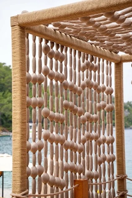 A cream screen of rounded wrapped forms inside rope-covered framing on the seafront deck at So Beach.
