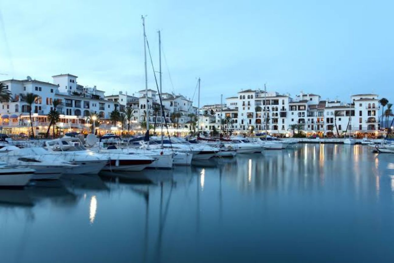 Moored yachts and whitewashed Andalusian buildings at dusk in Puerto de la Duquesa, Manilva — western Costa del Sol