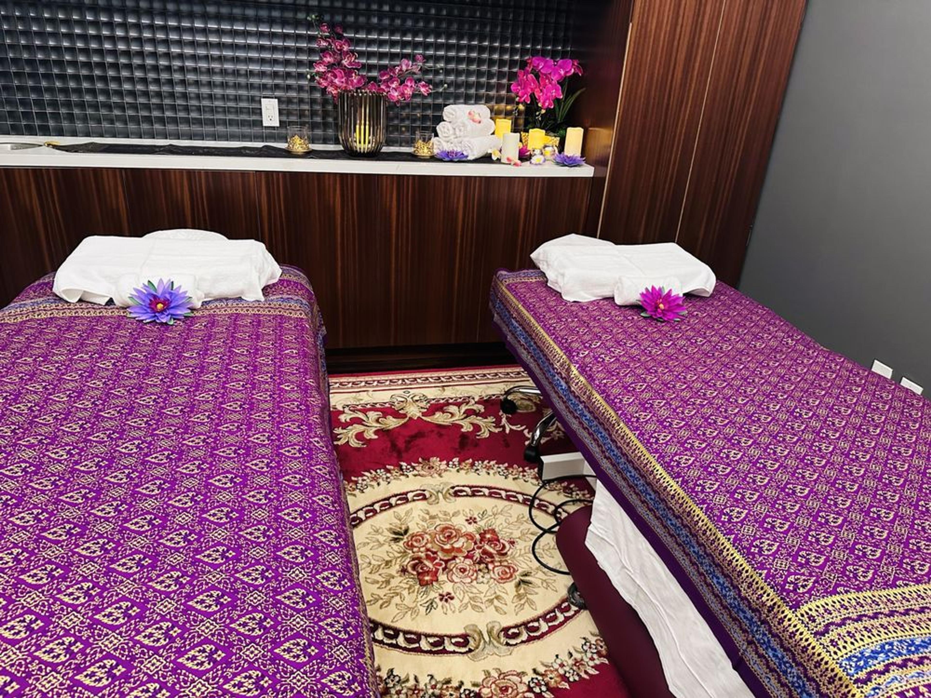 The couples treatment room at Kamla, two beds made up in Thai-pattern covers with towels, lotus flowers, and candles