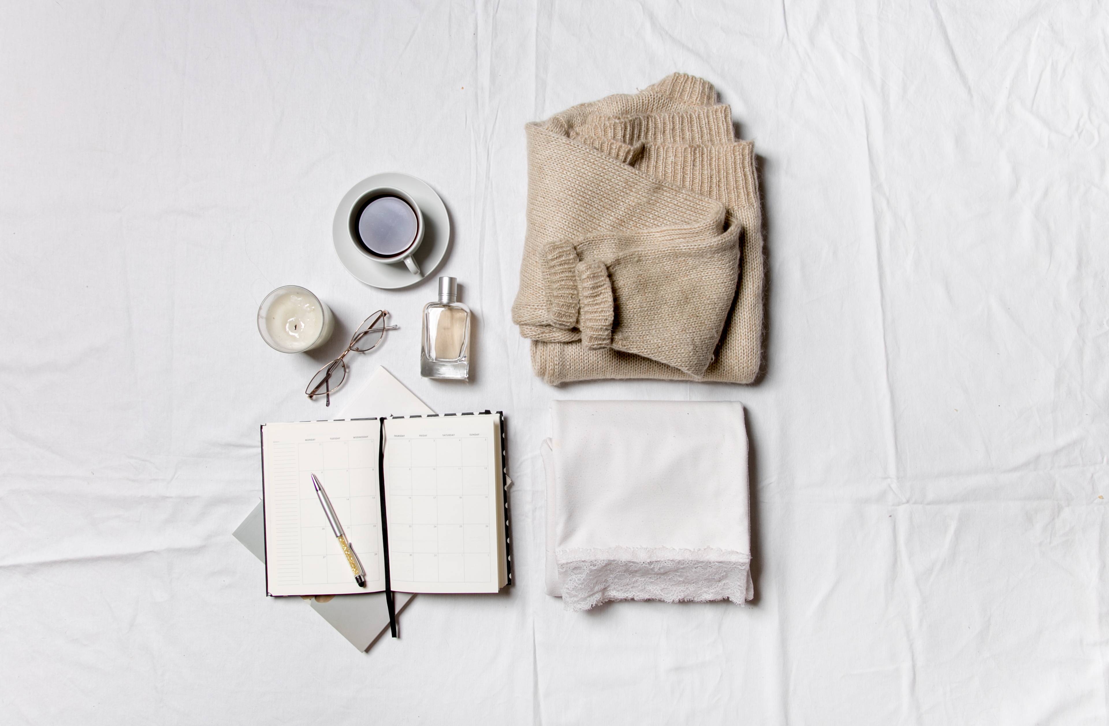 Flat lay of notebook, a sweater, towel and coffee