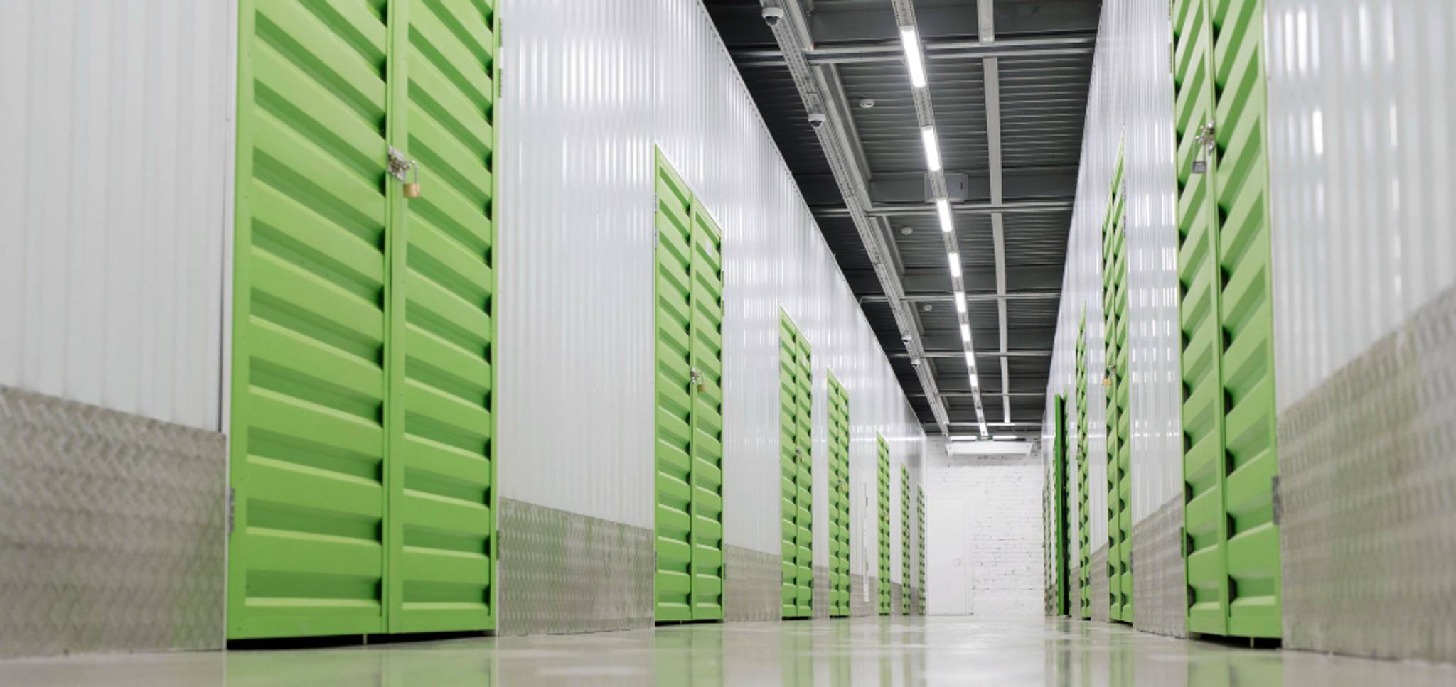 Long row of green storage doors in a well-lit facility