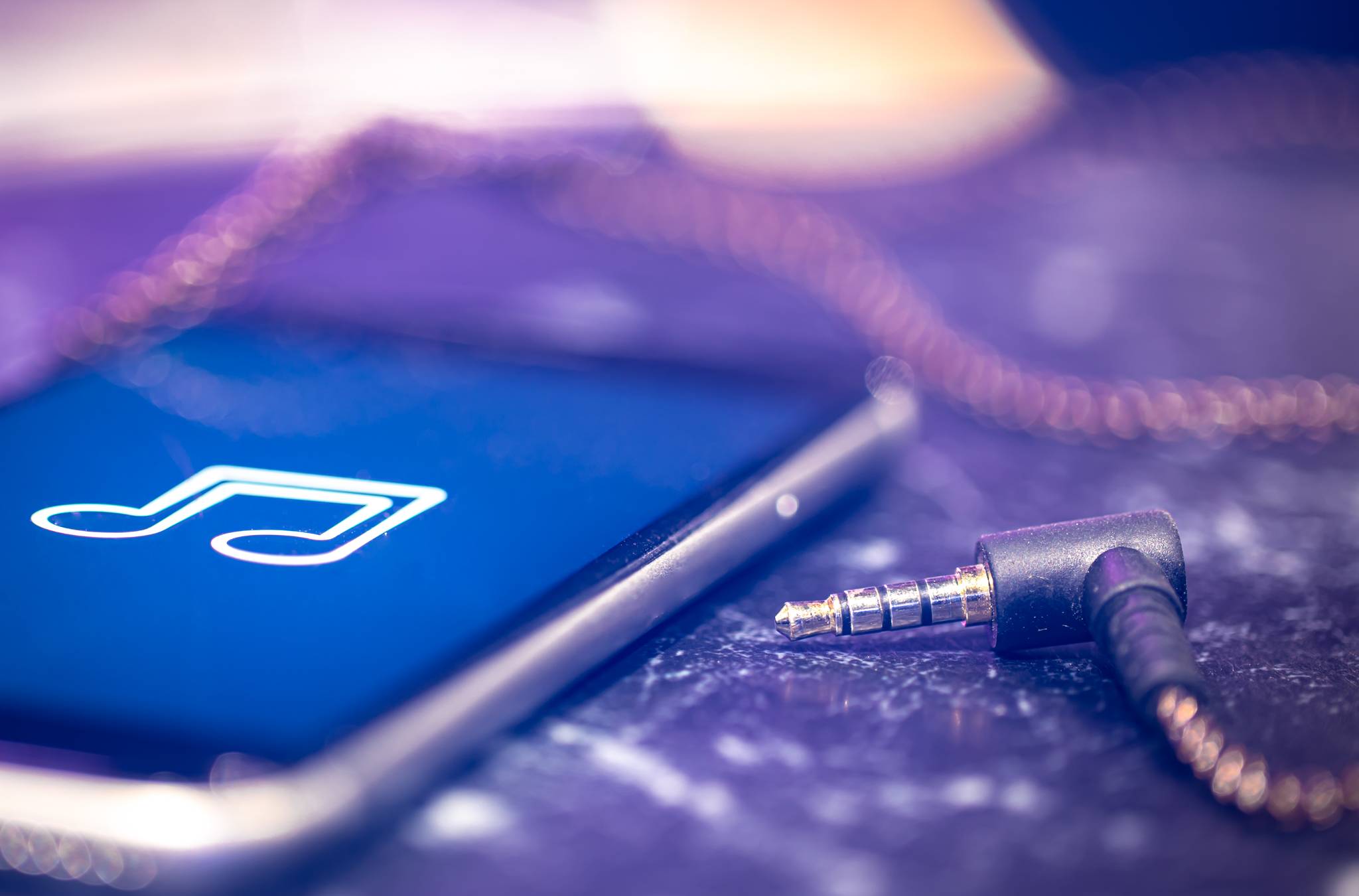 Music background with a music listening icon on the phone and headphones.