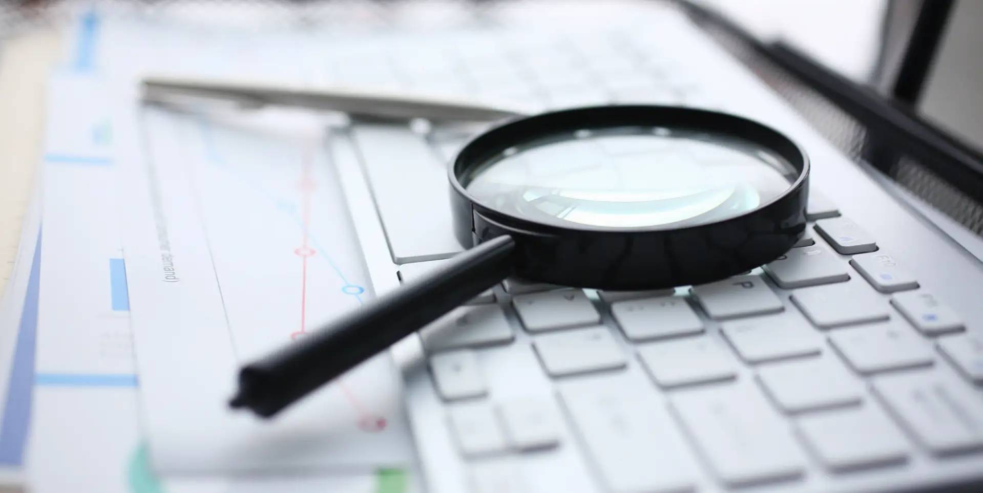 A magnifiying glass laying on a keyboard