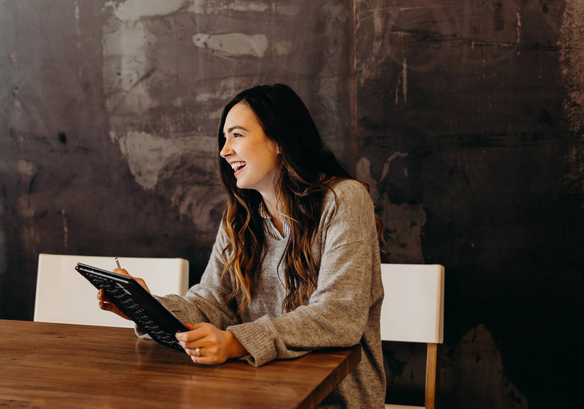 woman smiling with tablet at table