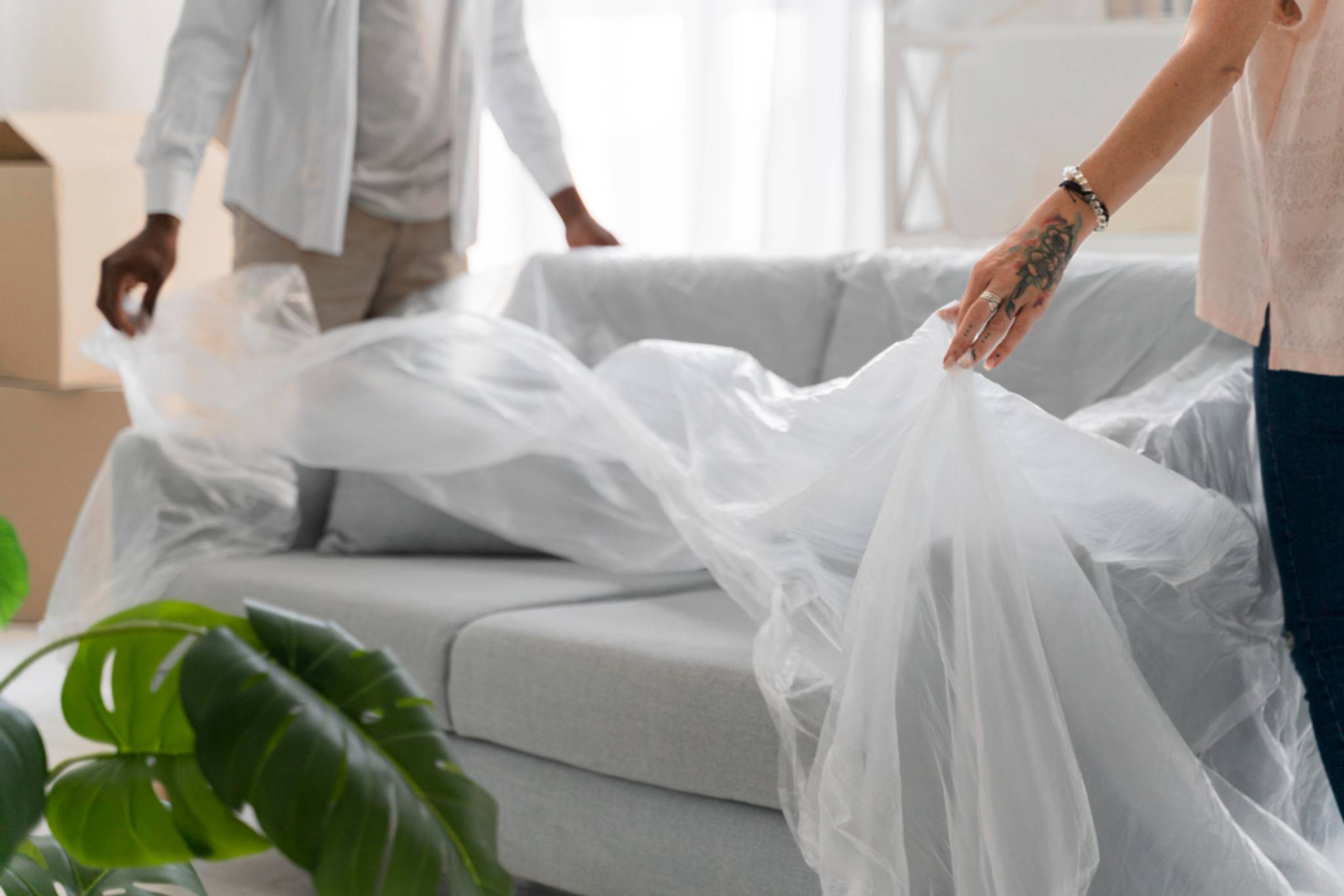 couple wrapping sofa in cover