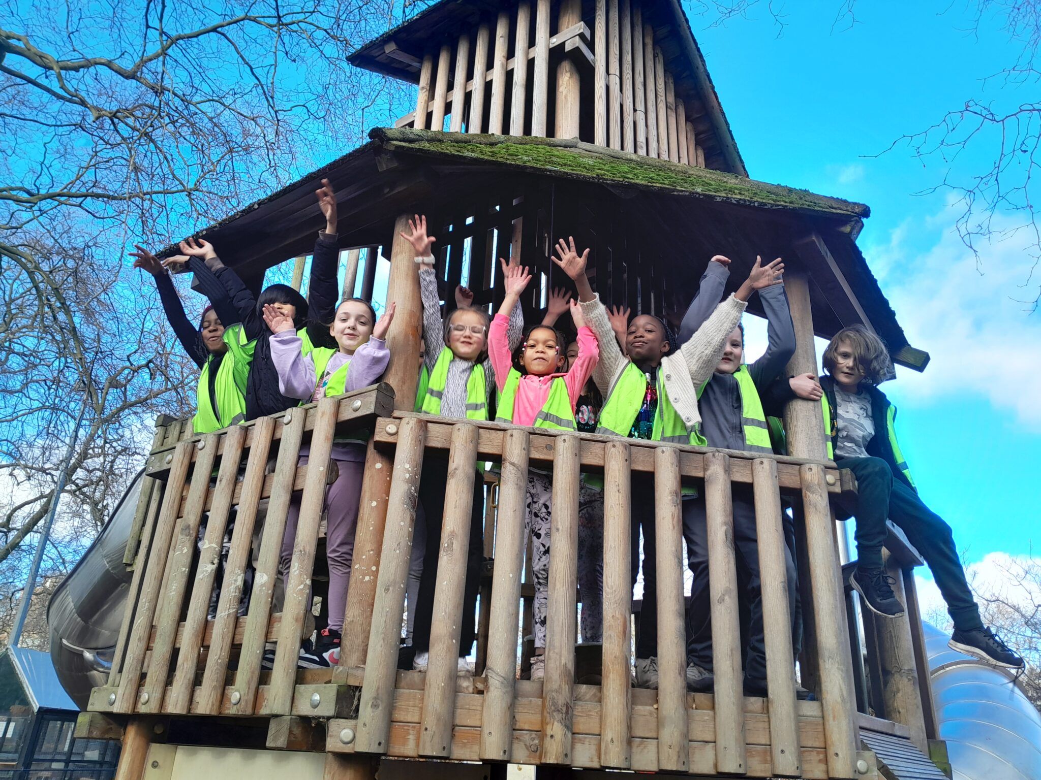 Kids with hands up on wooden climbing frame