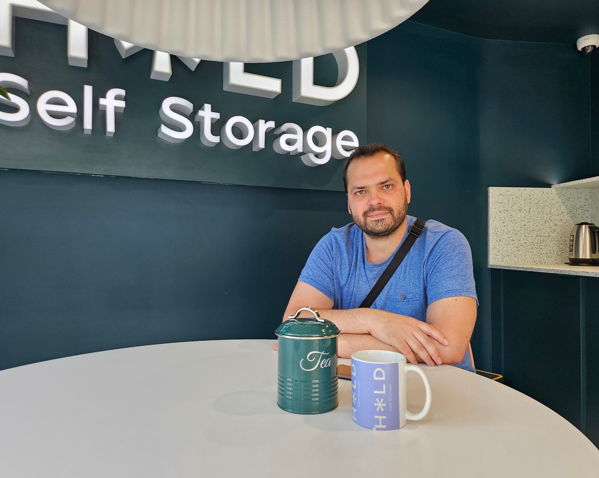 person smiling sitting at table with coffee mug