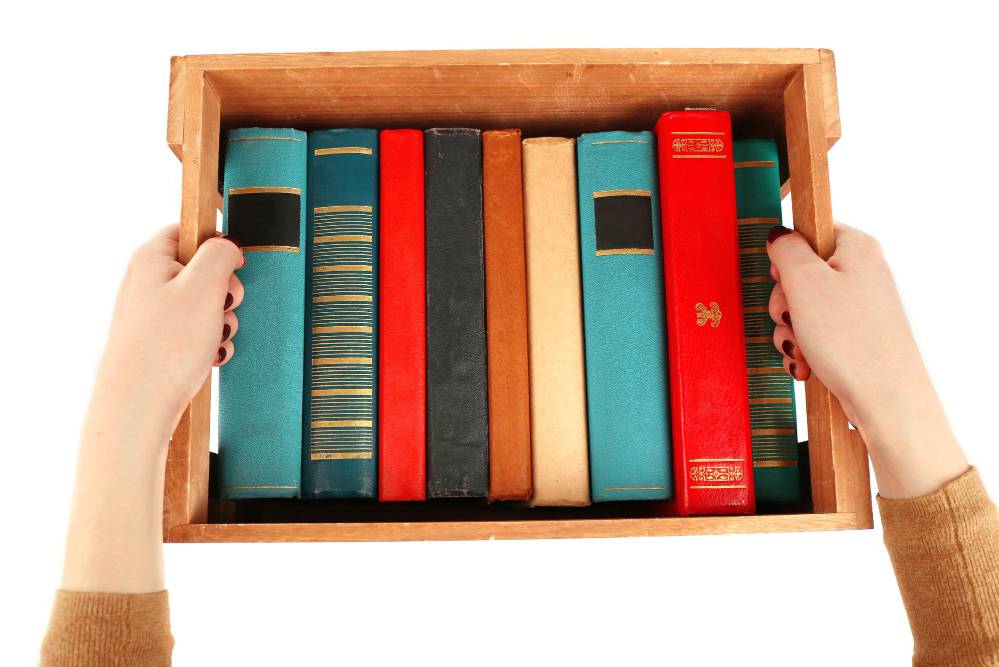 Someone carrying a wooden box filled with books